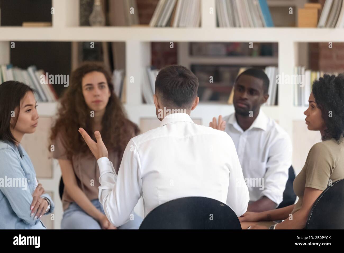 Homme de vue arrière partageant des problèmes avec divers groupes lors de la séance de thérapie, thérapeute masculin, psychologue parlant avec les patients à la réunion, traitement de la toxicomanie Banque D'Images