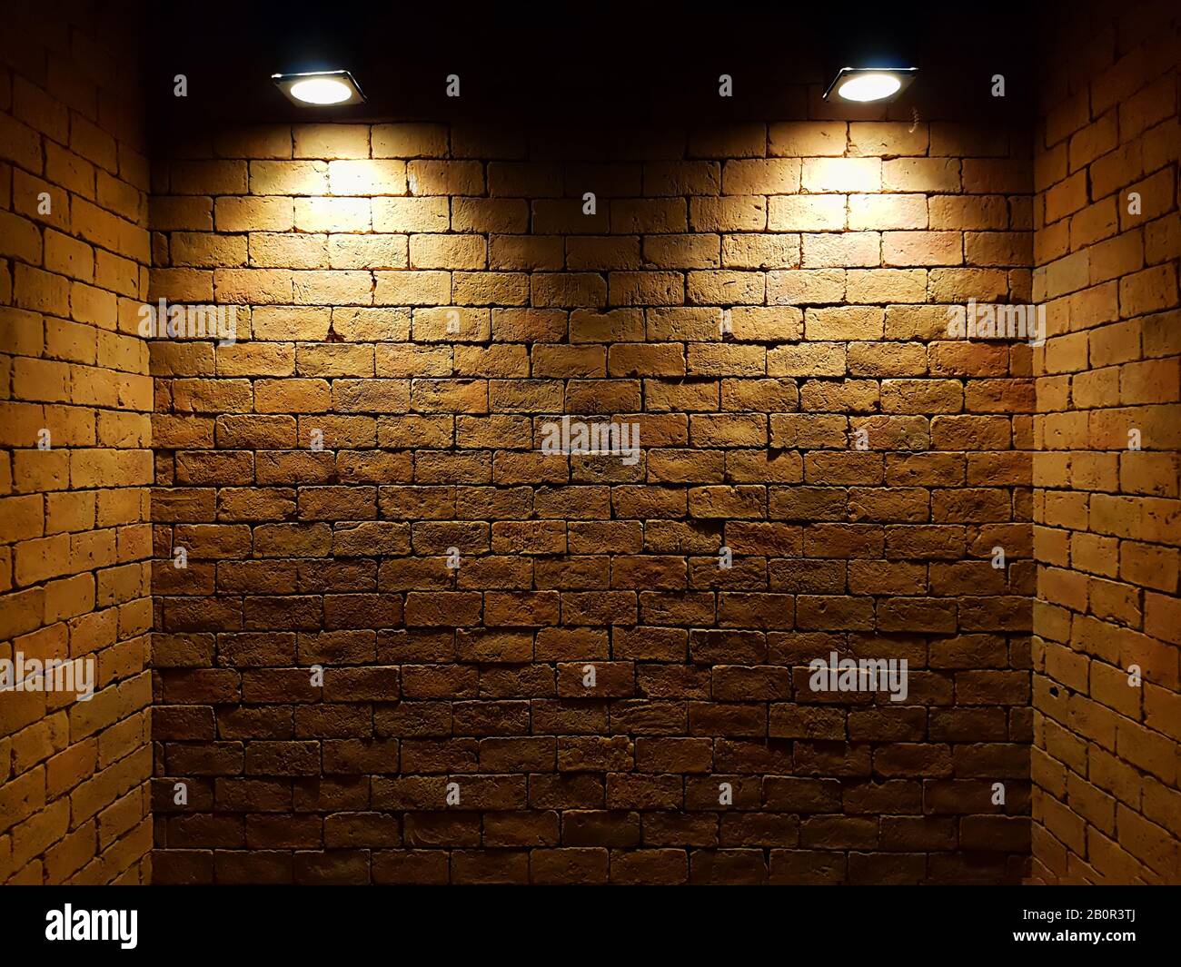 mur de briques vieux abstrait dans l'obscurité avec deux projecteurs, ton clair chaud. mur de briques dans la pièce vide. fond de mur de briques pour le papier peint Banque D'Images