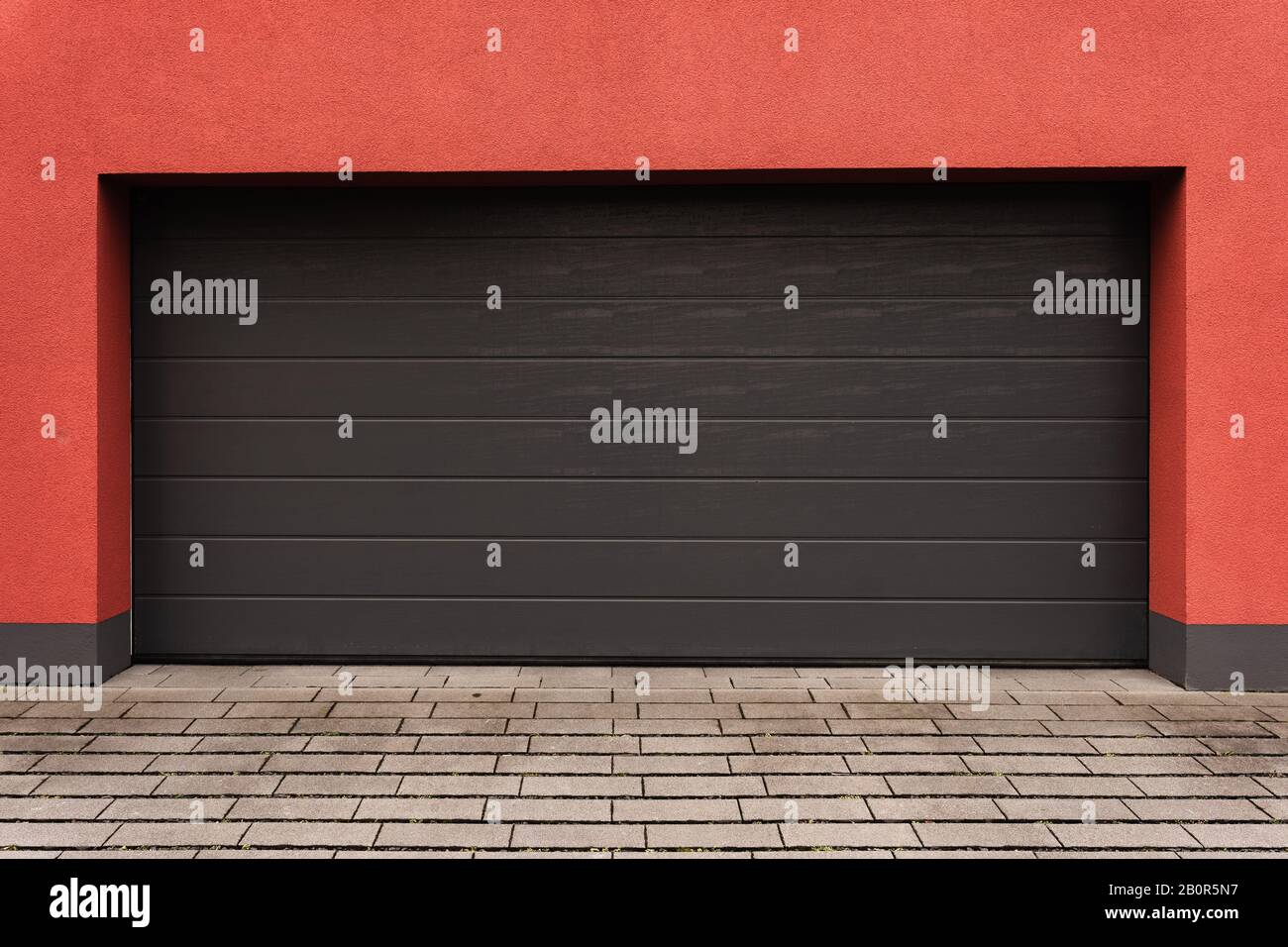 Garage moderne avec porte grise et mur rouge Banque D'Images