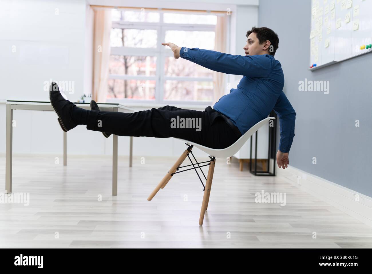 Photo De L'Homme Tombant Sur La Chaise Au Bureau Banque D'Images