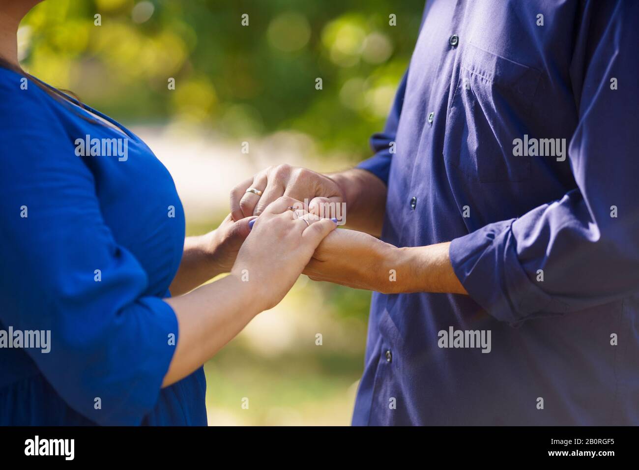 Un homme en chemise violette et femme chemisier bleu tenant les mains Banque D'Images