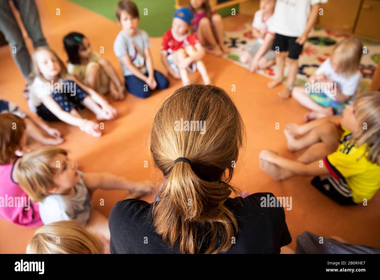 L'éducateur est assis avec des enfants à la maternelle dans un cercle à l'étage, Cologne, Rhénanie-du-Nord-Westphalie, Allemagne Banque D'Images