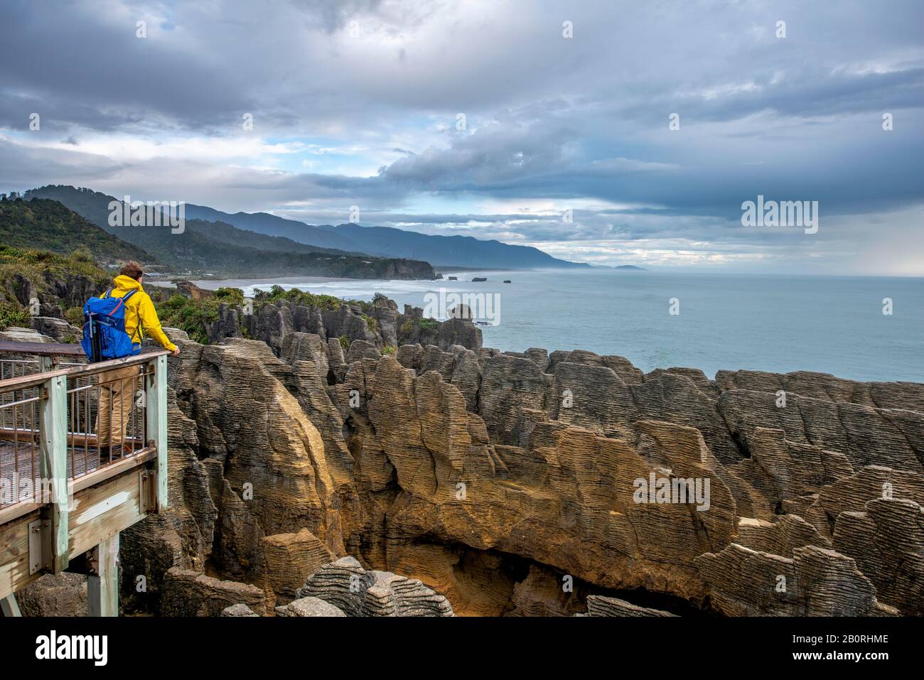 Jeune homme sur une plate-forme d'observation regardant le paysage côtier avec des roches de grès, Pancake Rocks, parc national de Paparoa, Punakaiki, côte ouest, Sud Banque D'Images