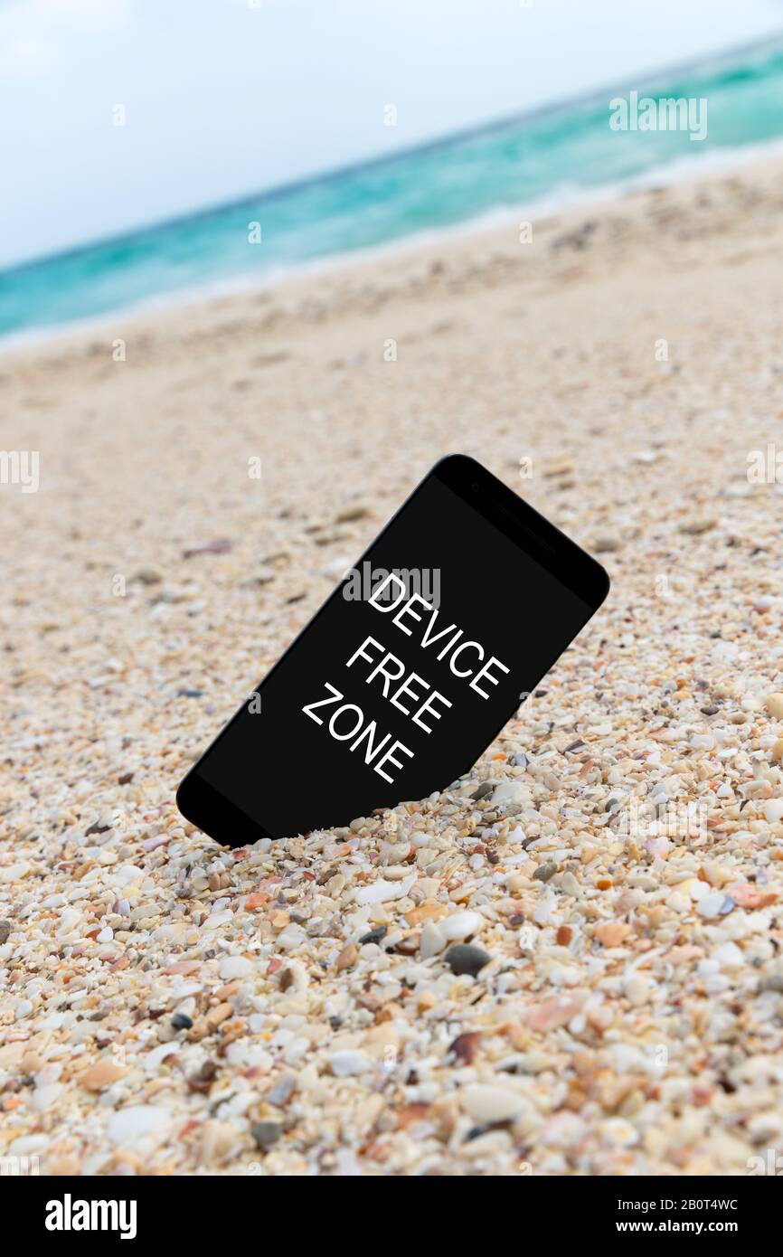 Spartphone avec dispositif texte zone libre écrit dans son écran placé dans le sable d'une plage. Médias sociaux gadget Internet dépendance concept Banque D'Images