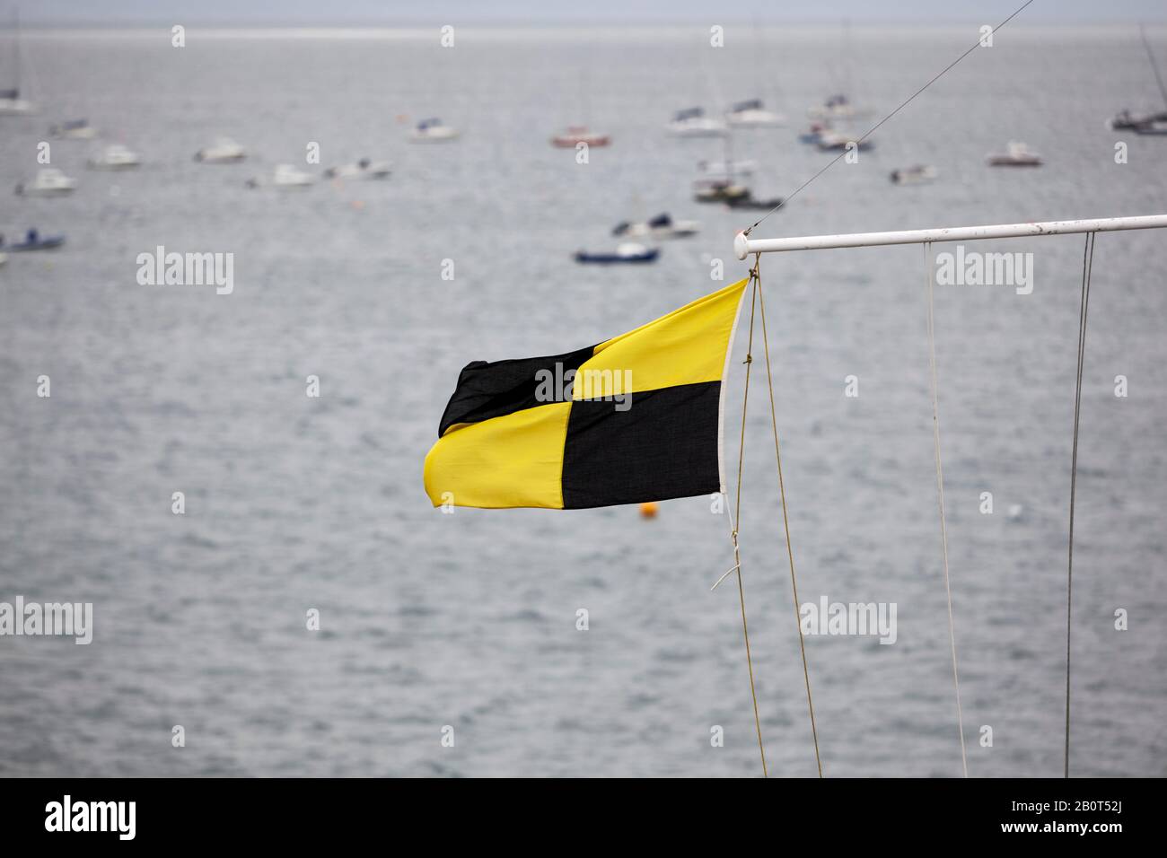 Drapeau nautique jaune et noir flamant à la fin du poteau du drapeau du  club de voile avec hors de la zone de mise au point des bateaux à ancre  dans la