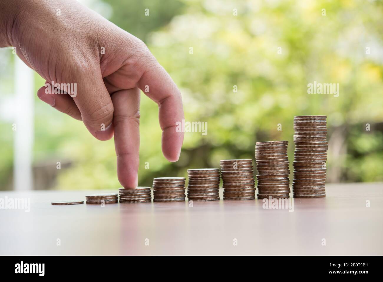 Les doigts marchent sur la pile de pièces ou la pile d'argent Banque D'Images
