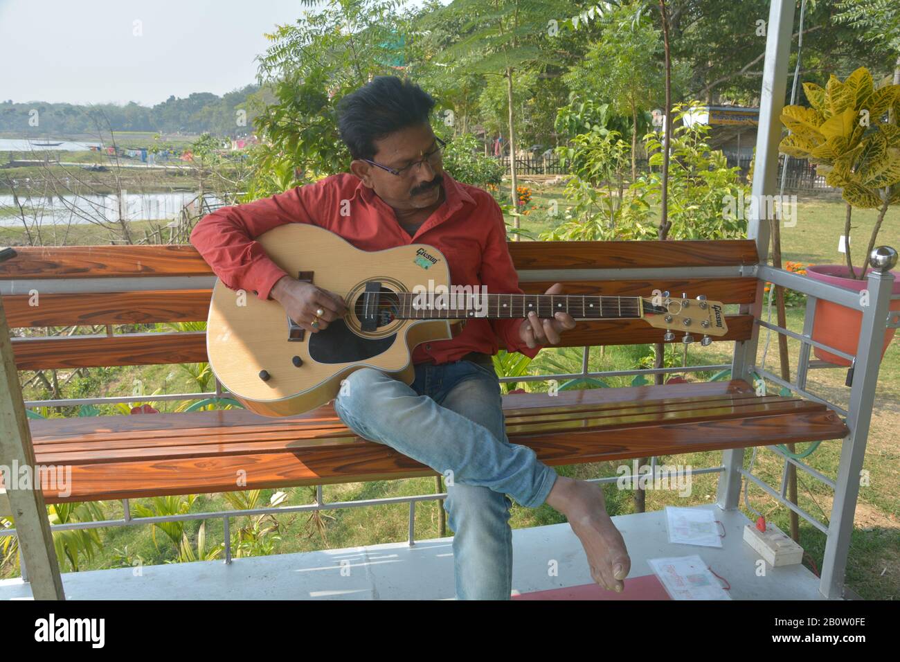 Gros plan sur une personne jouant de la guitare assise sur un banc dans un parc ou un jardin dans le Bengale occidental, en Inde, focalisation sélective Banque D'Images