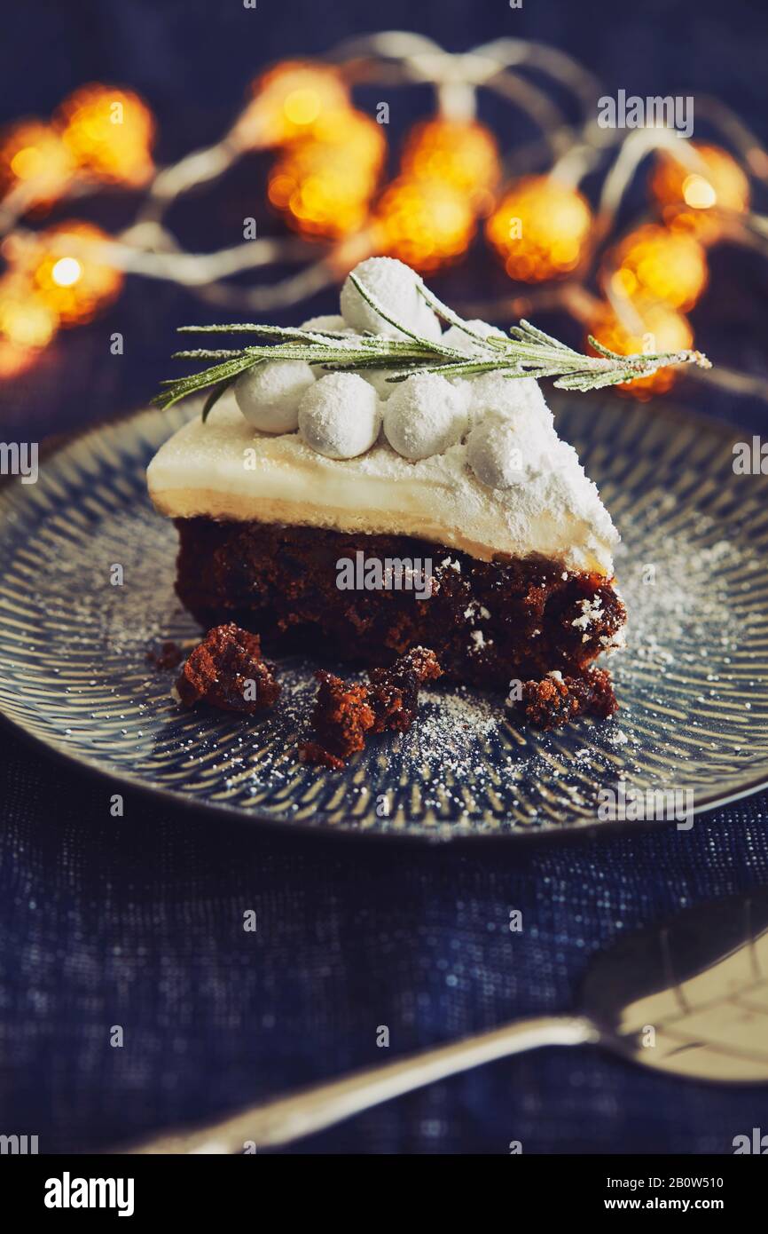 Gros plan sur une tranche de gâteau d'Halloween avec givrage blanc et brins de romarin. Banque D'Images