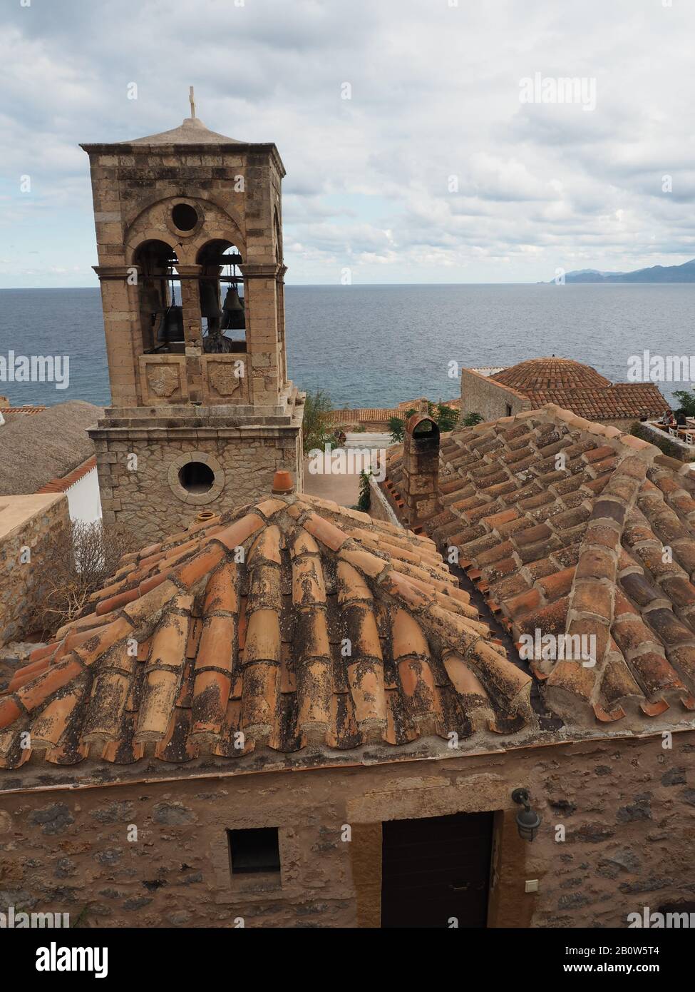 Elkomenos Christos église tour et toits de tuiles dans la ville fortifiée de Monemvasia, Laconia, Péloponnèse, Grèce. Bleu mer derrière. Banque D'Images