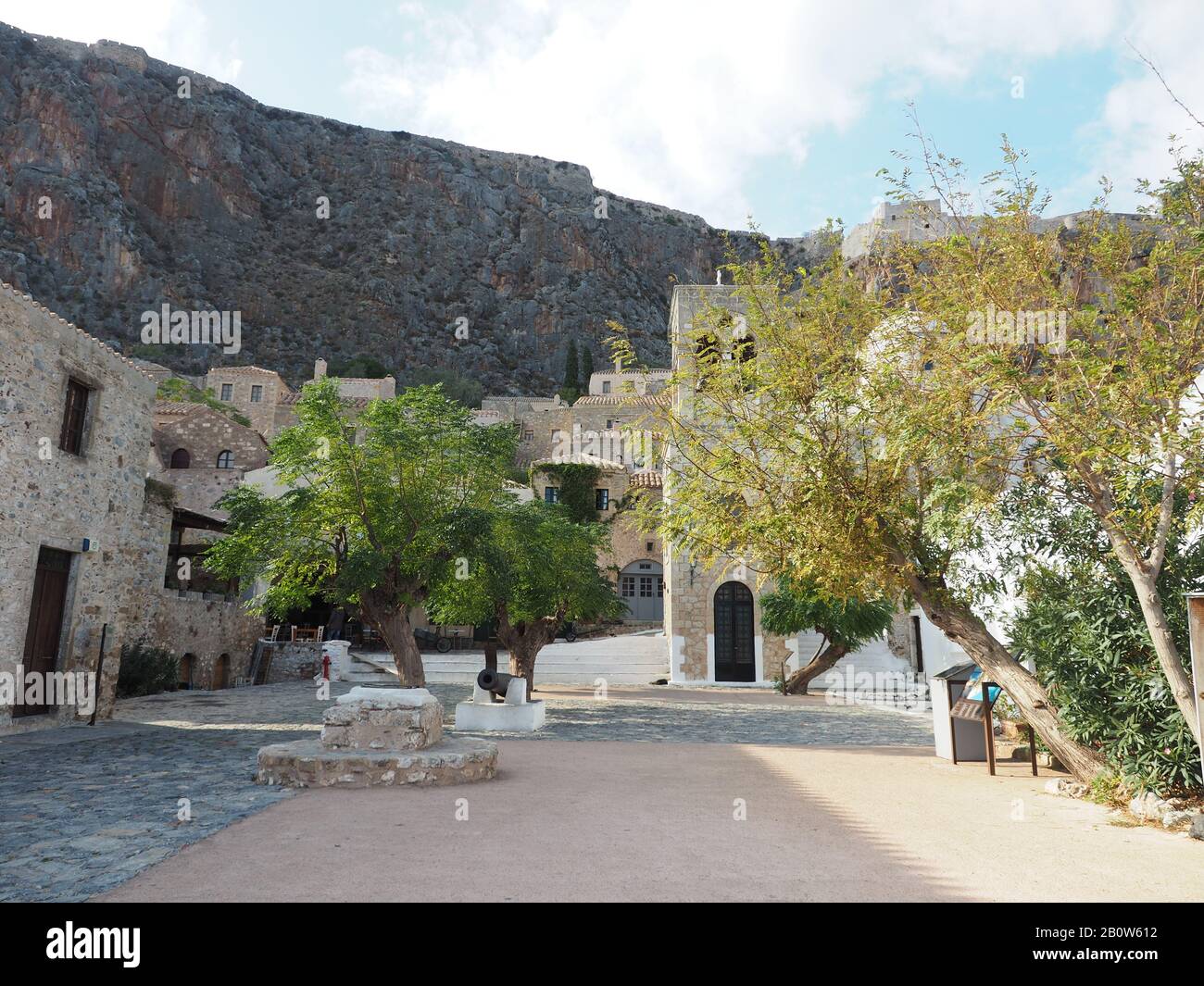 Arbres et Elkomenos Église de Christos dans la place centrale de la ville fortifiée de Monemvasia, Laconia, Péloponnèse, Grèce. Ruines sur la ligne d'horizon. Banque D'Images
