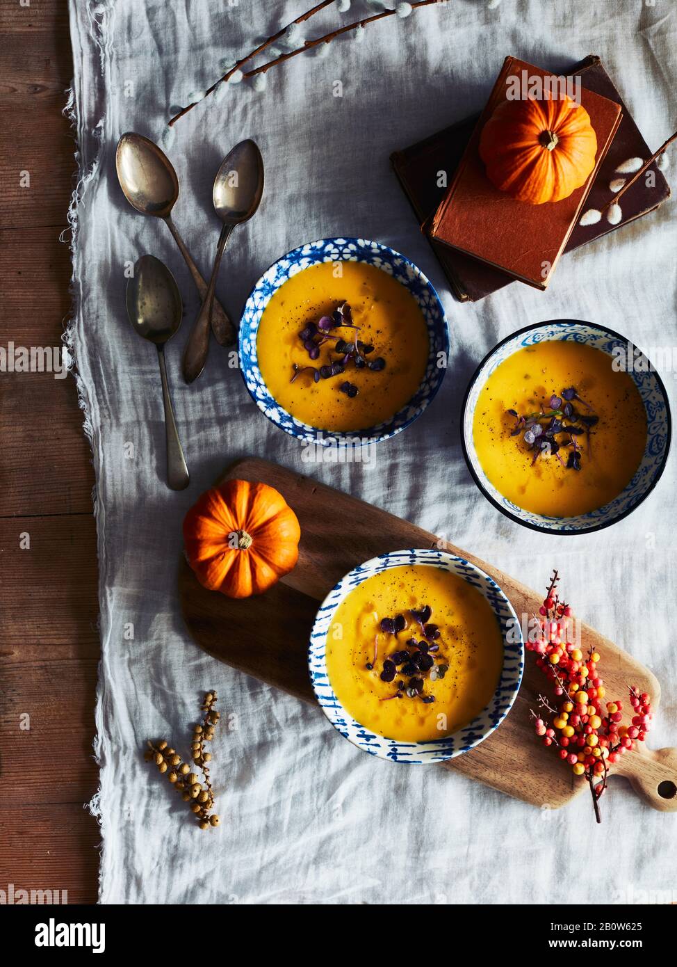 Grand angle, gros plan de citrouilles orange et bols de soupe de citrouille sur une table. Banque D'Images