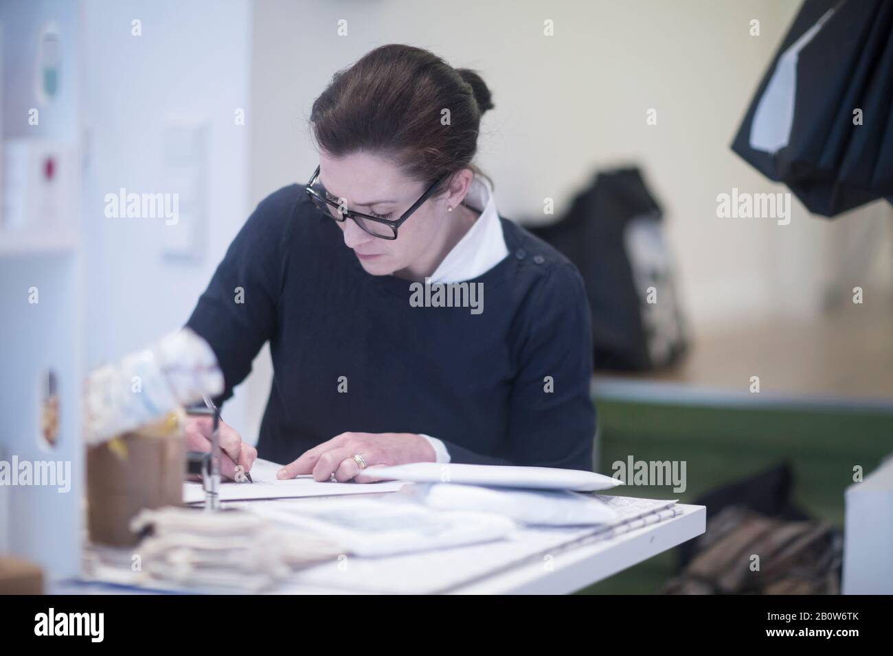 Lunettes de port sur mesure pour femme, assise à la table, écriture. Banque D'Images