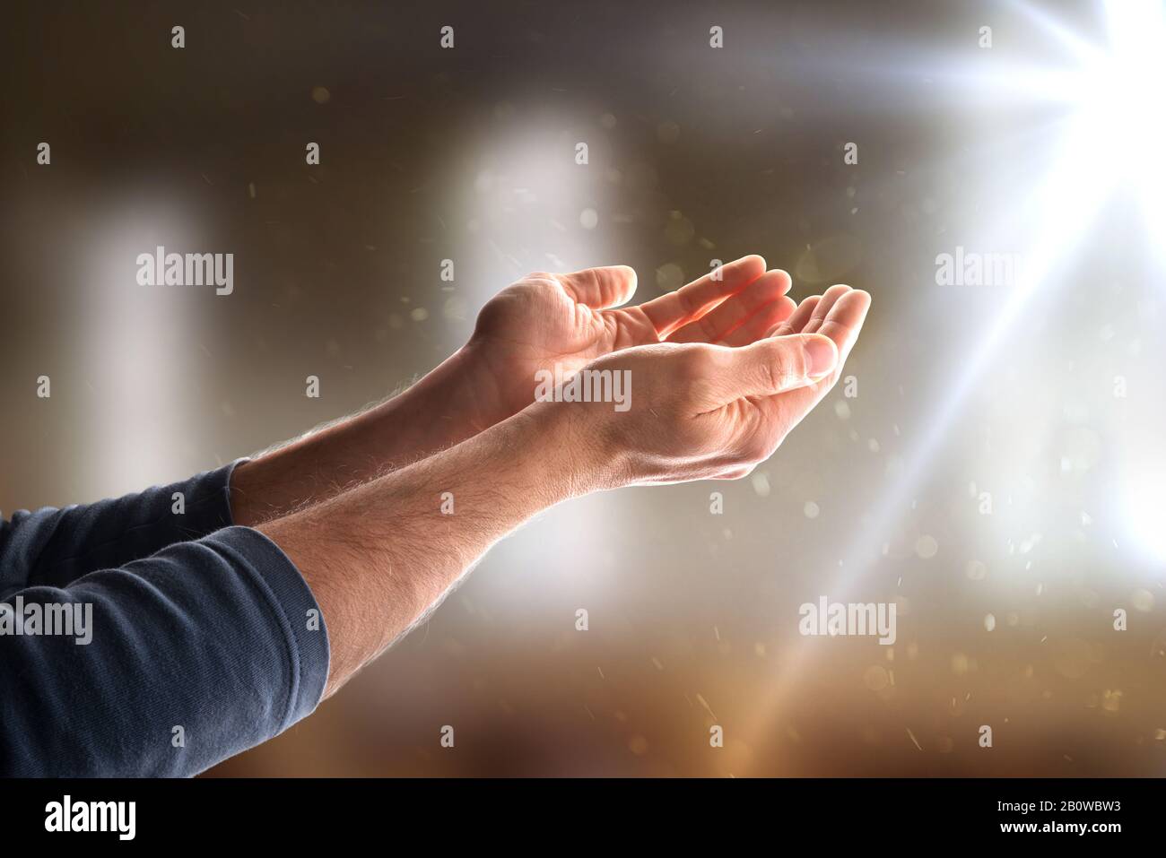 mains avec des paumes dans une église avec des étincelles et des rayons de lumière. Composition horizontale Banque D'Images
