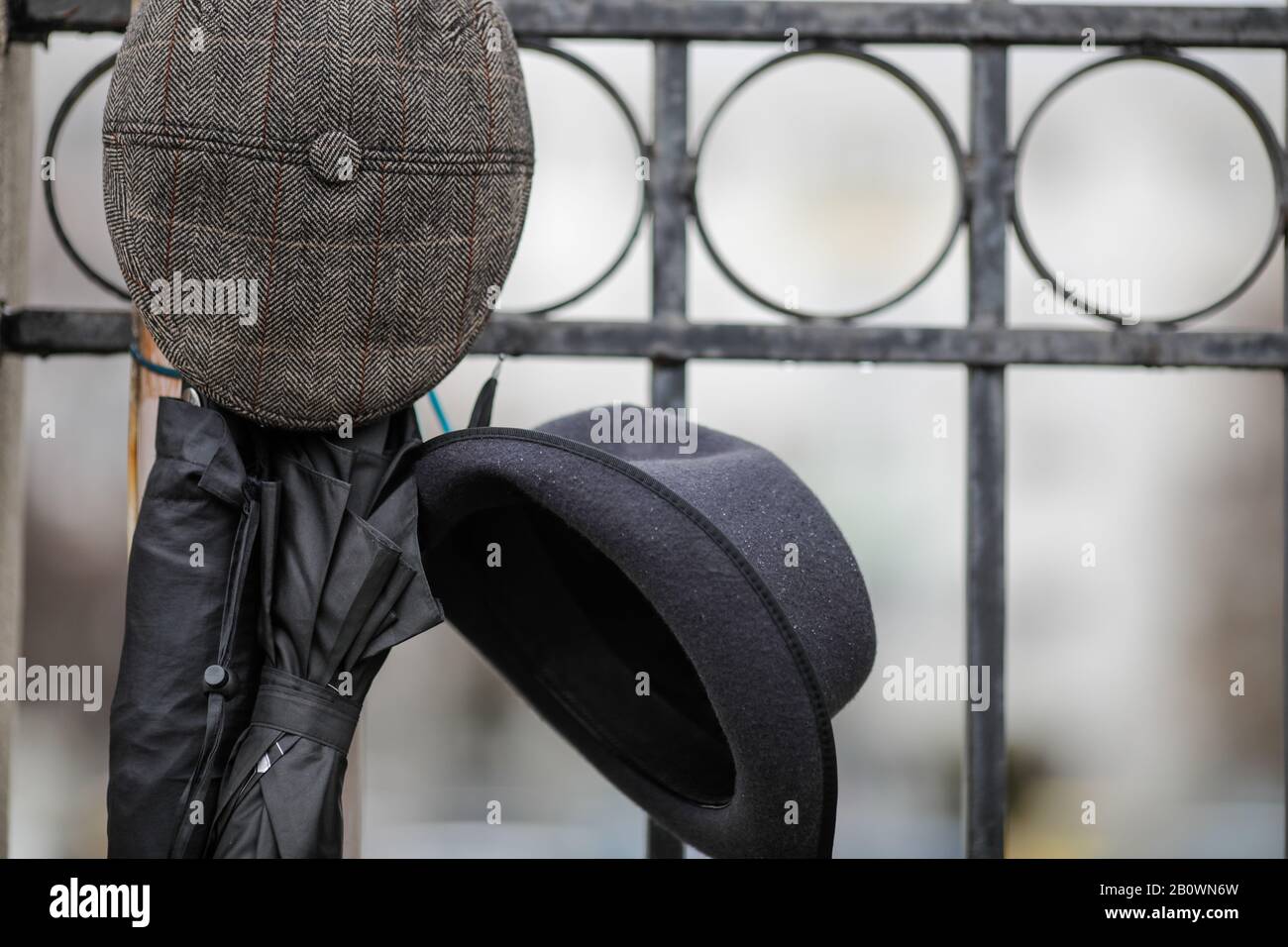 Faible profondeur de champ (foyer sélectif) image avec deux chapeaux hommes et deux parapluies noirs pendus sur une clôture pendant un jour pluvieux. Banque D'Images