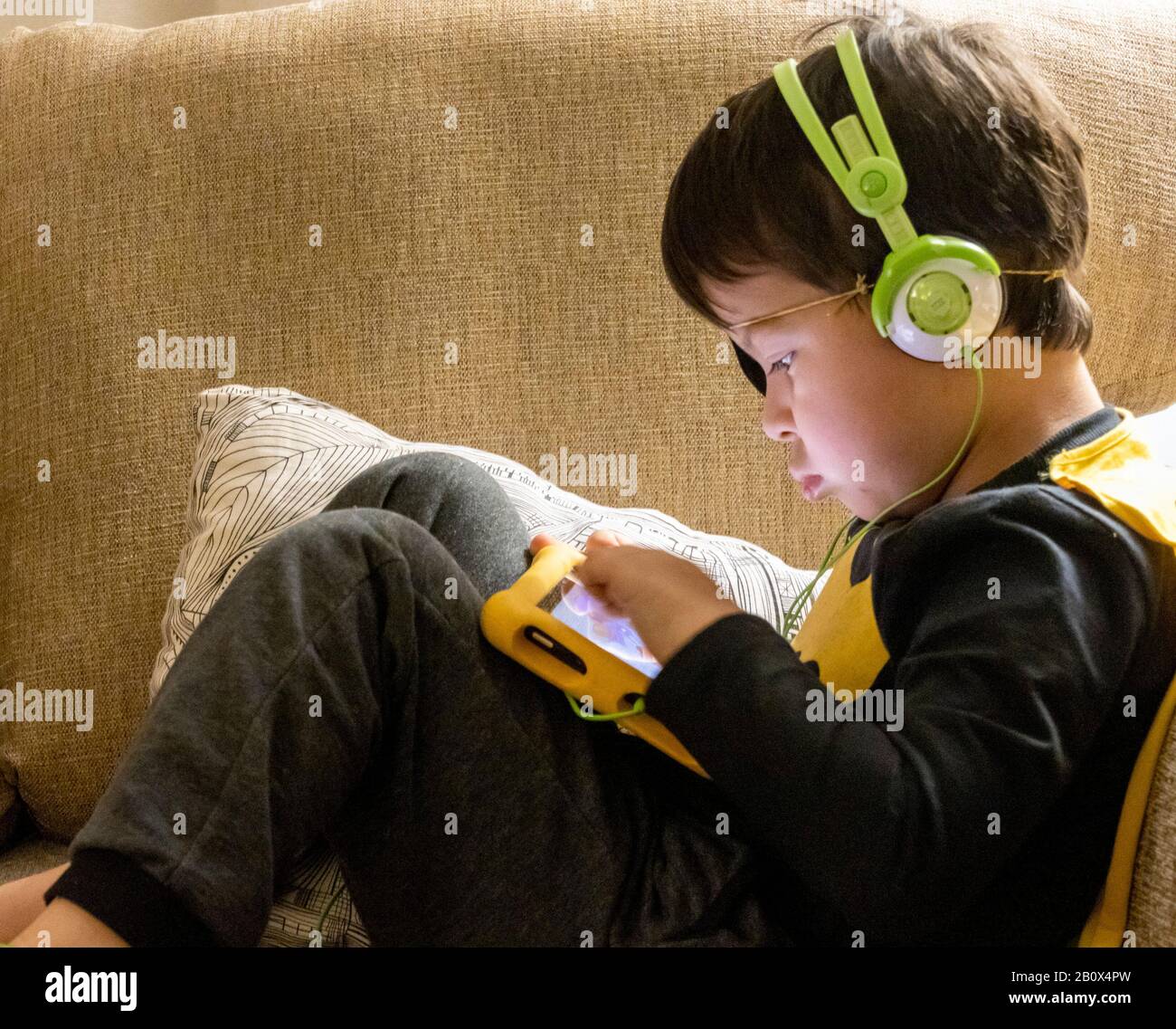 Les enfants qui jouent sur une tablette Amazon Fire écoutent des écouteurs Banque D'Images