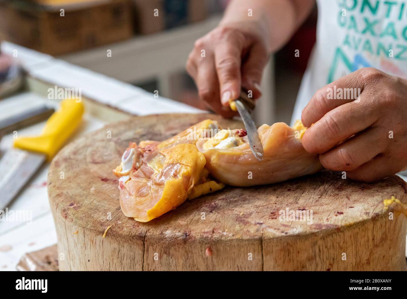 Oaxaca, Mexique - une femme coupe le poulet sur le marché Sánchez Pascuas. Banque D'Images