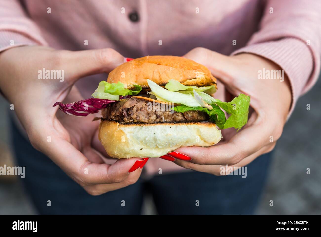 Une jeune femme mangeant un hamburger de viande de canard dans un marché alimentaire de rue. Banque D'Images