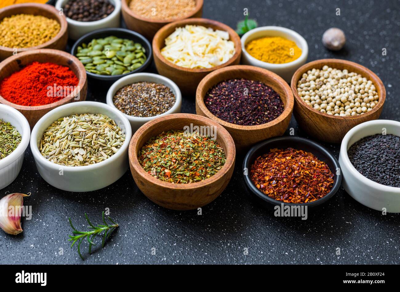 Variété d'épices, d'herbes et de graines colorées sur fond de pierre noire. Banque D'Images