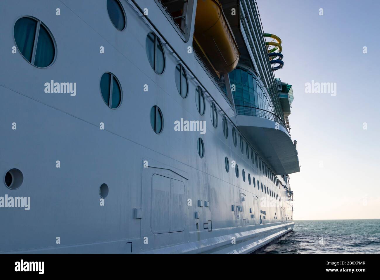 Vue latérale d'un bateau de croisière massif en mer, fenêtres en cabine en premier plan et ciel crépuscule/aube moelleux en arrière-plan Banque D'Images