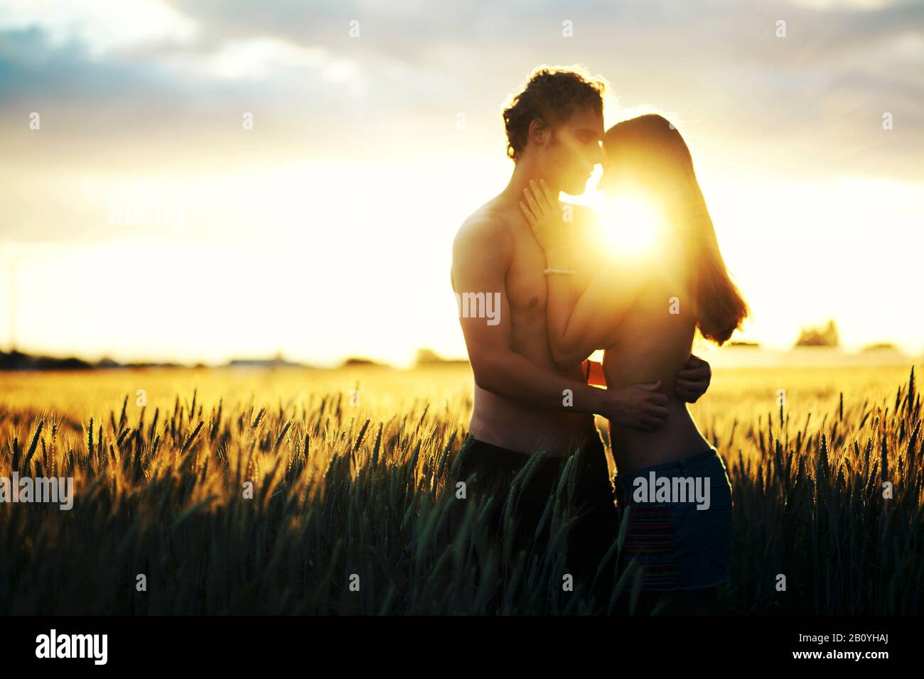 Jeune couple amoureux dans le champ de grain embrassant contre la lumière, Banque D'Images