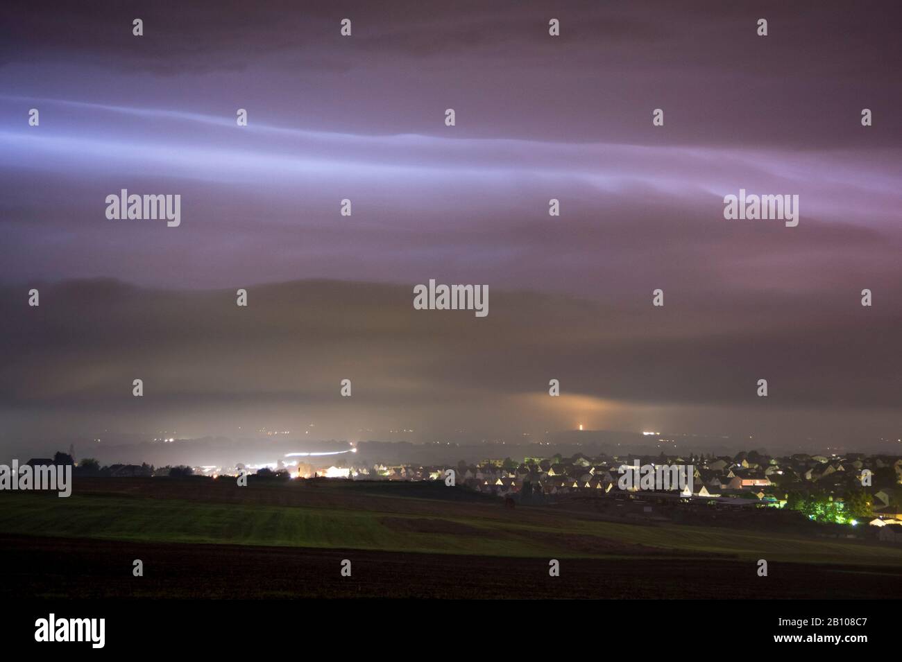 Nuage nocturne d'un orage illuminé par des éclairs de lumière derrière Langgöns, Hessen, Allemagne Banque D'Images