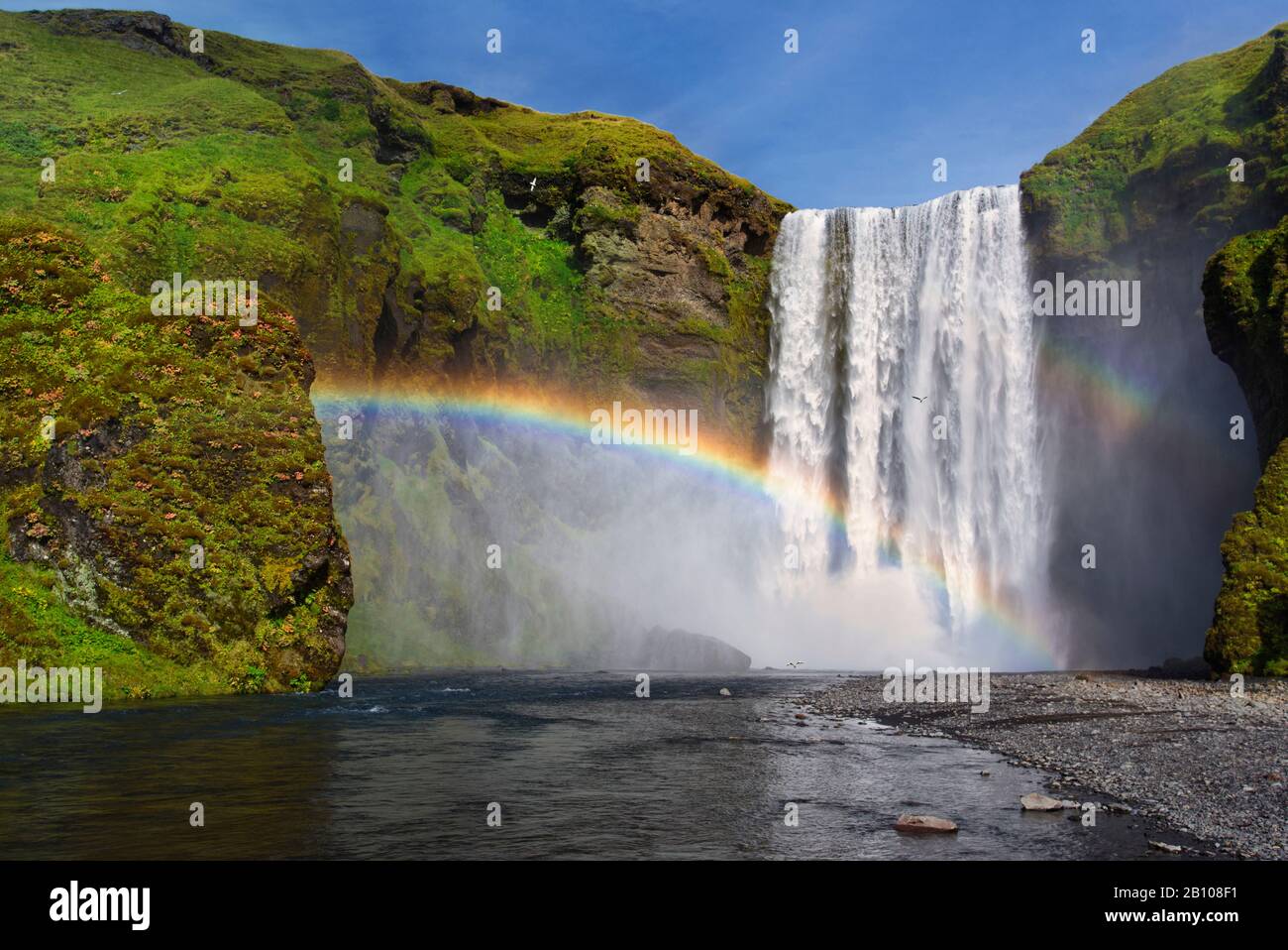 Chute d'eau de Skogafoss au soleil avec arc-en-ciel, Skogar, Islande Banque D'Images