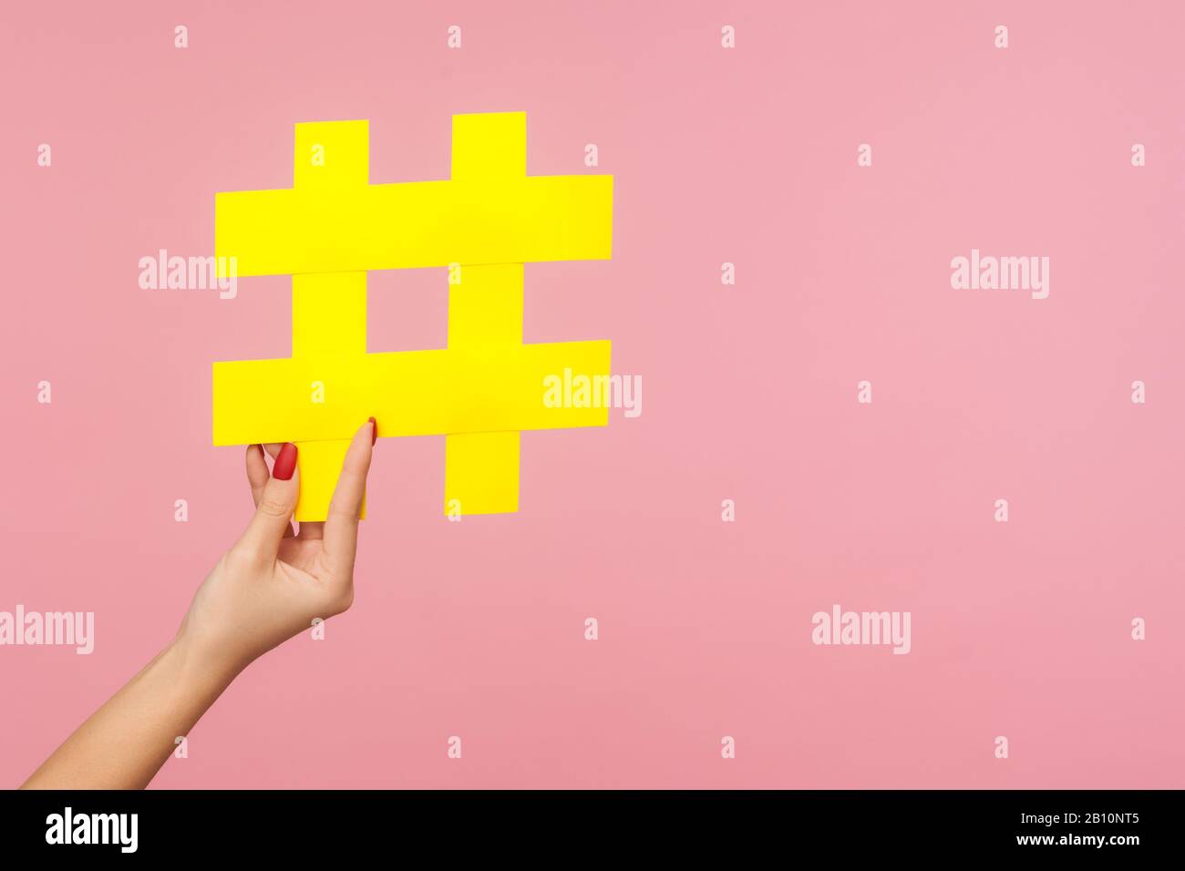 Gros plan de main tenant le grand symbole hashtag de papier jaune à côté de l'espace de copie, signe de hachage de contenu médiatique célèbre, marketing de médias sociaux et promo de blog Banque D'Images