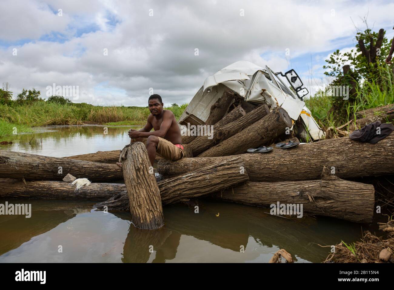 Homme assis sur des troncs d'arbres sur une rivière, Mozambique, Afrique Banque D'Images