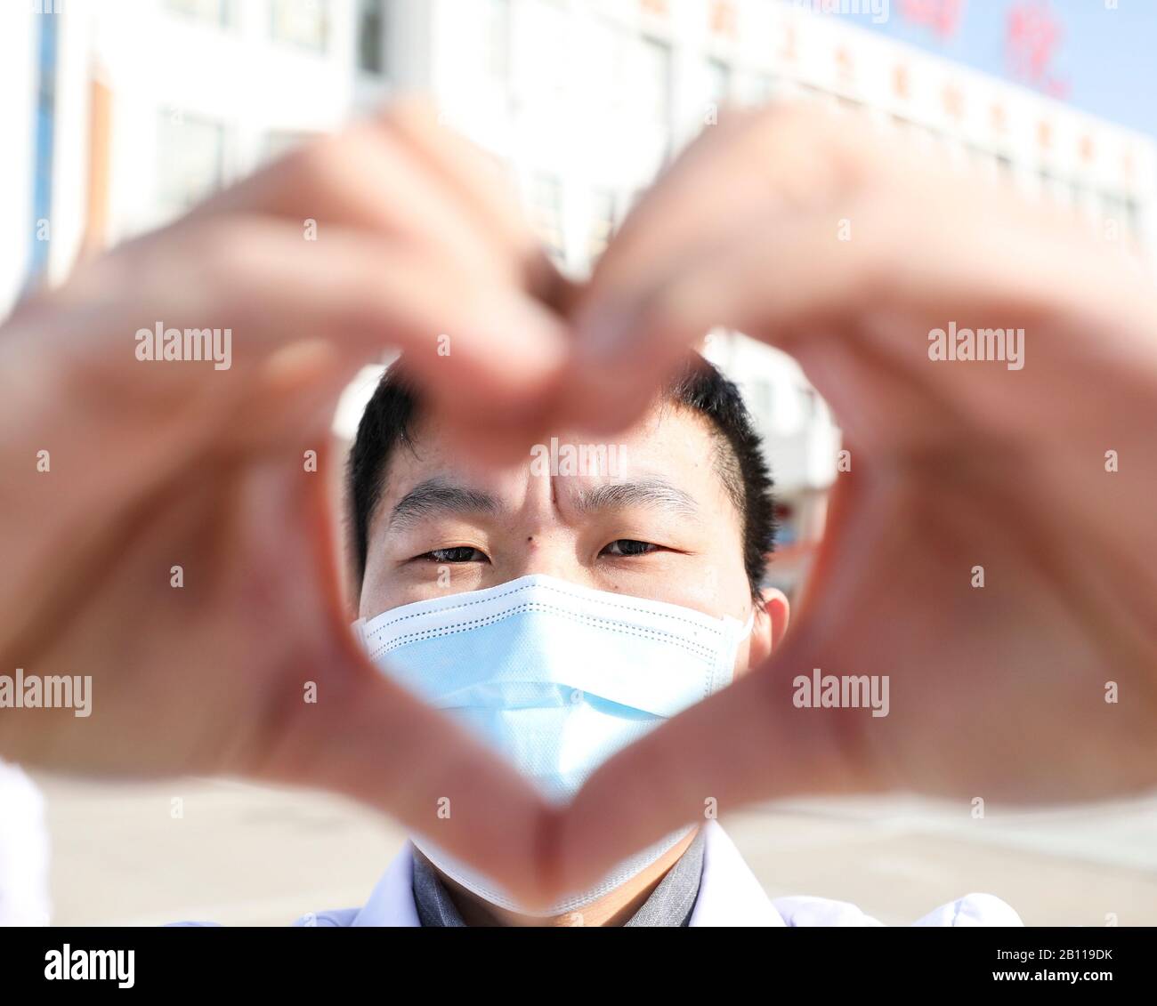 Un médecin chinois masqué fait un cœur avec ses mains lorsqu'il revient avec d'autres collègues à ses propres postes après un isolement de 14 jours et Banque D'Images