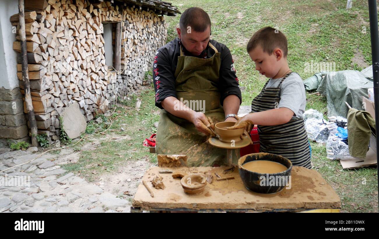 Musée Ethnographique En Plein Air 'Etar' - Gabrovo, Bulgarie. 06 septembre 2019 - XVII Foire internationale des métiers d'art traditionnels. Le maître enseigne un chil Banque D'Images Musée Ethnographique En Plein Air 'Etar' - Gabrovo, Bulgarie. 06 septembre 2019 - XVII Foire internationale des métiers d'art traditionnels. Le maître enseigne un chil Banque D'Images