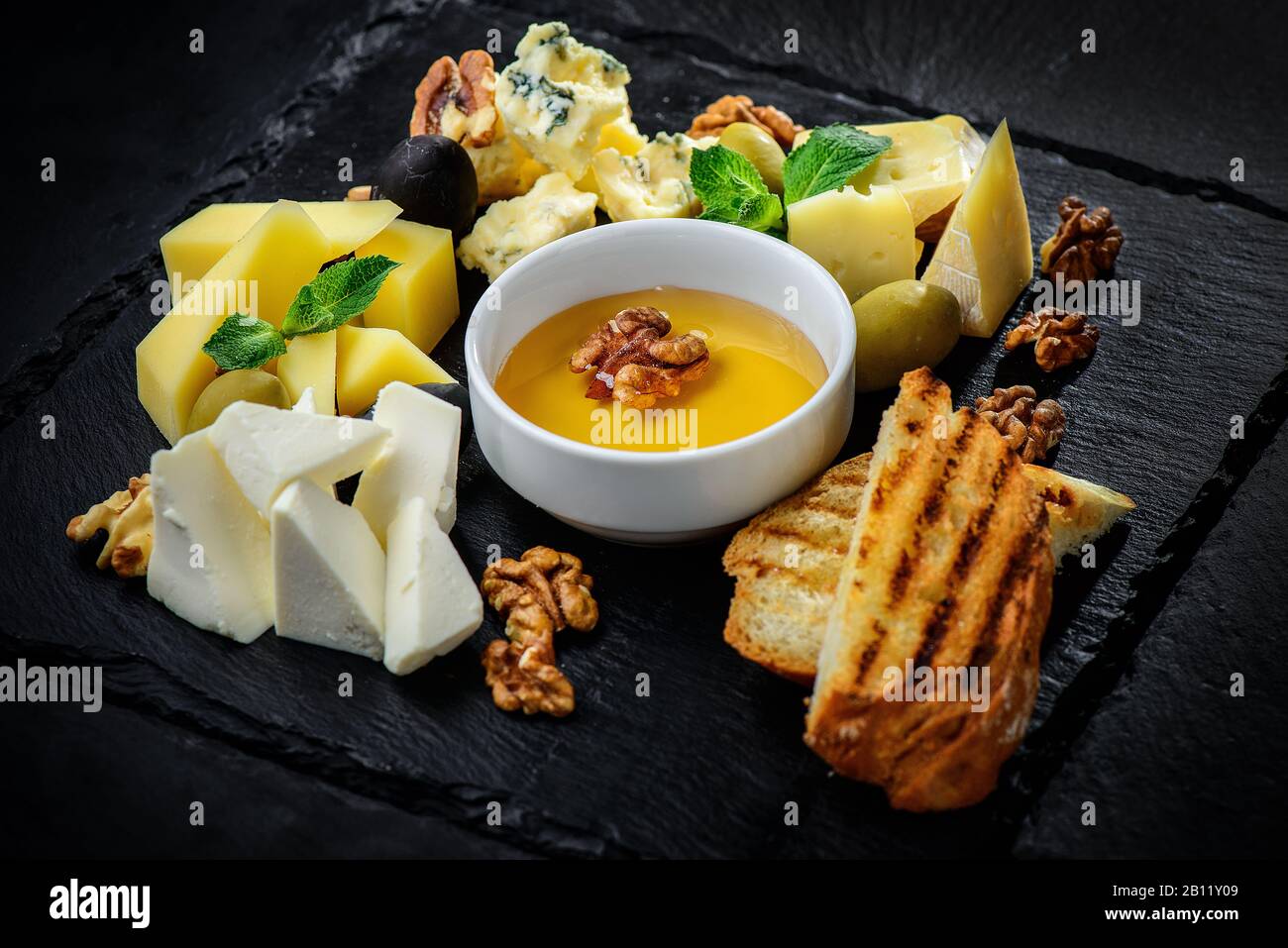 Assiette de fromages Dorblu, parmesan, Brie, Camembert et Roquefort sur fond noir texturé Banque D'Images