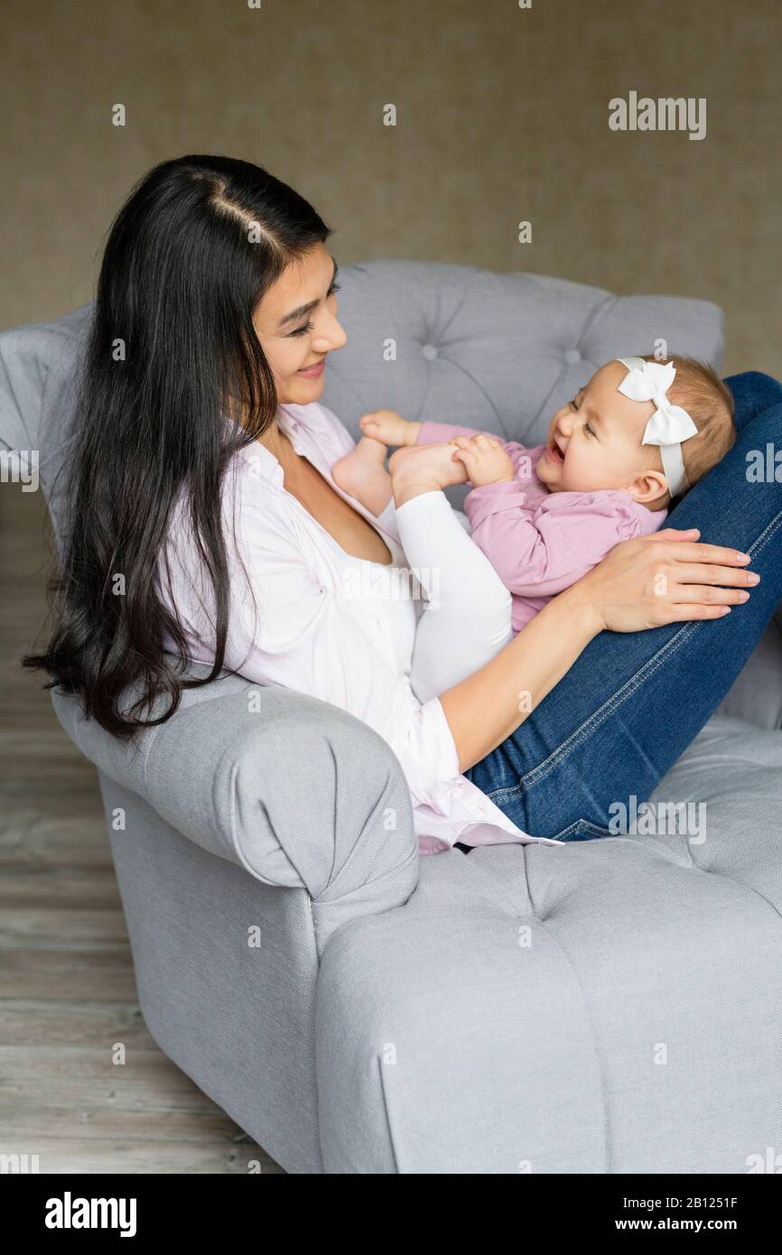 La mère est assise sur une chaise avec bébé Banque D'Images
