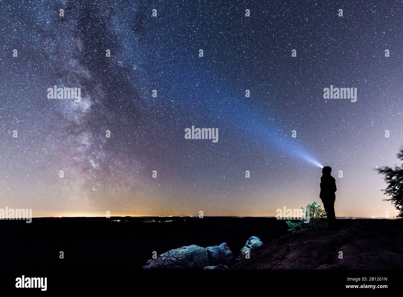 Femme avec phare sur le Pfaffenstein la nuit, faisceau de lumière, ciel étoilé, Elbe Sandstone Mountains, Saxe, Allemagne Banque D'Images