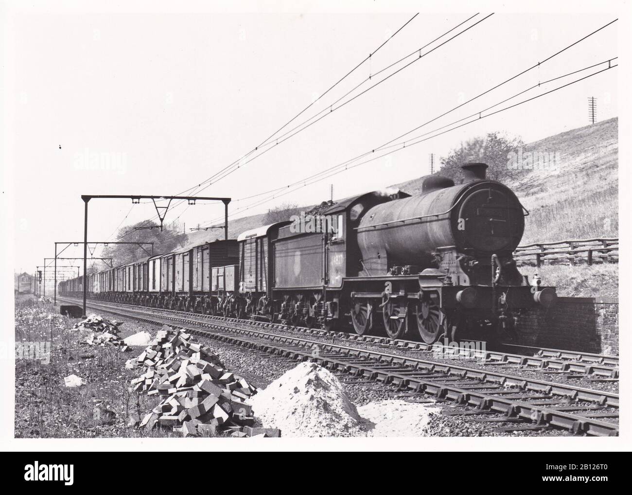 Photo noir et blanc vintage du train de locomotives à vapeur - E.R. Classe J 39 0-6-0 64827 sur un fret en haut passant Godley East Junction mai 1954. Banque D'Images