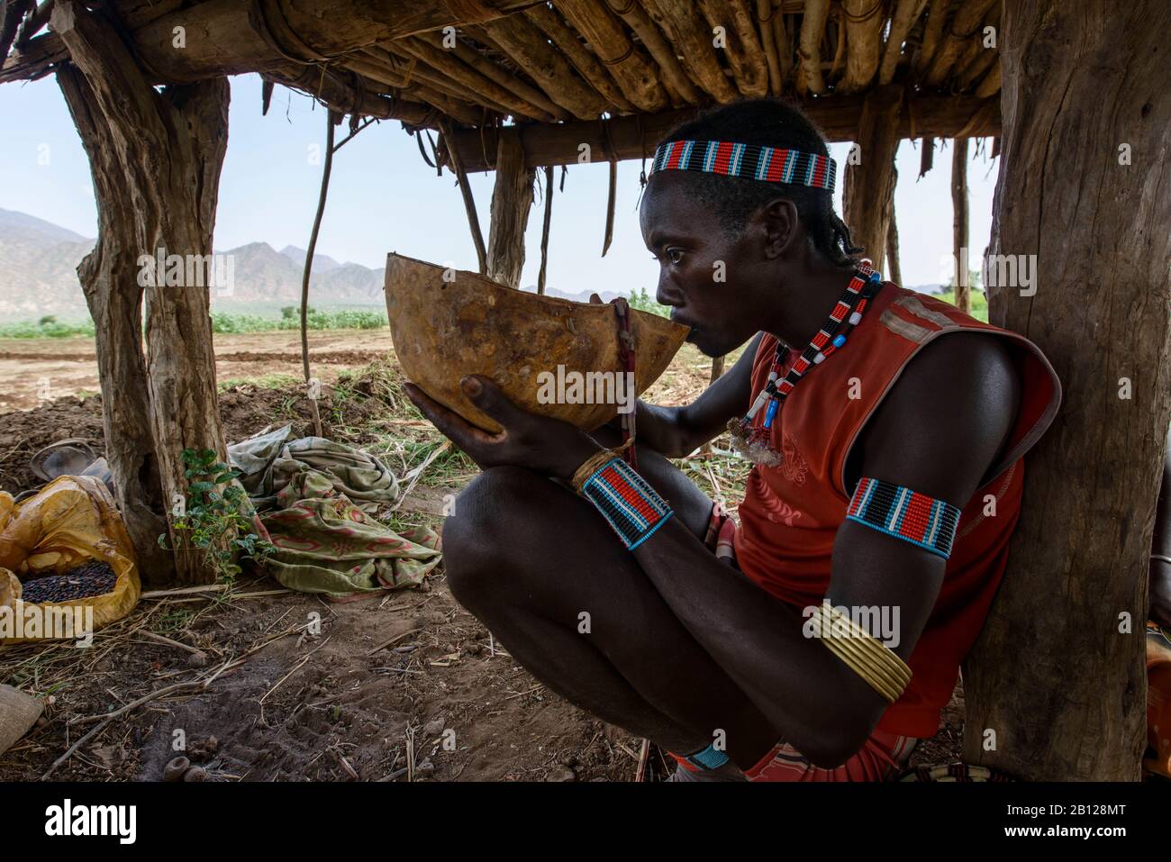 L'homme de la tribu Hamar dans la vallée d'Omo prend une pause et boire du vin maison, Weyto, Ethiopie Banque D'Images
