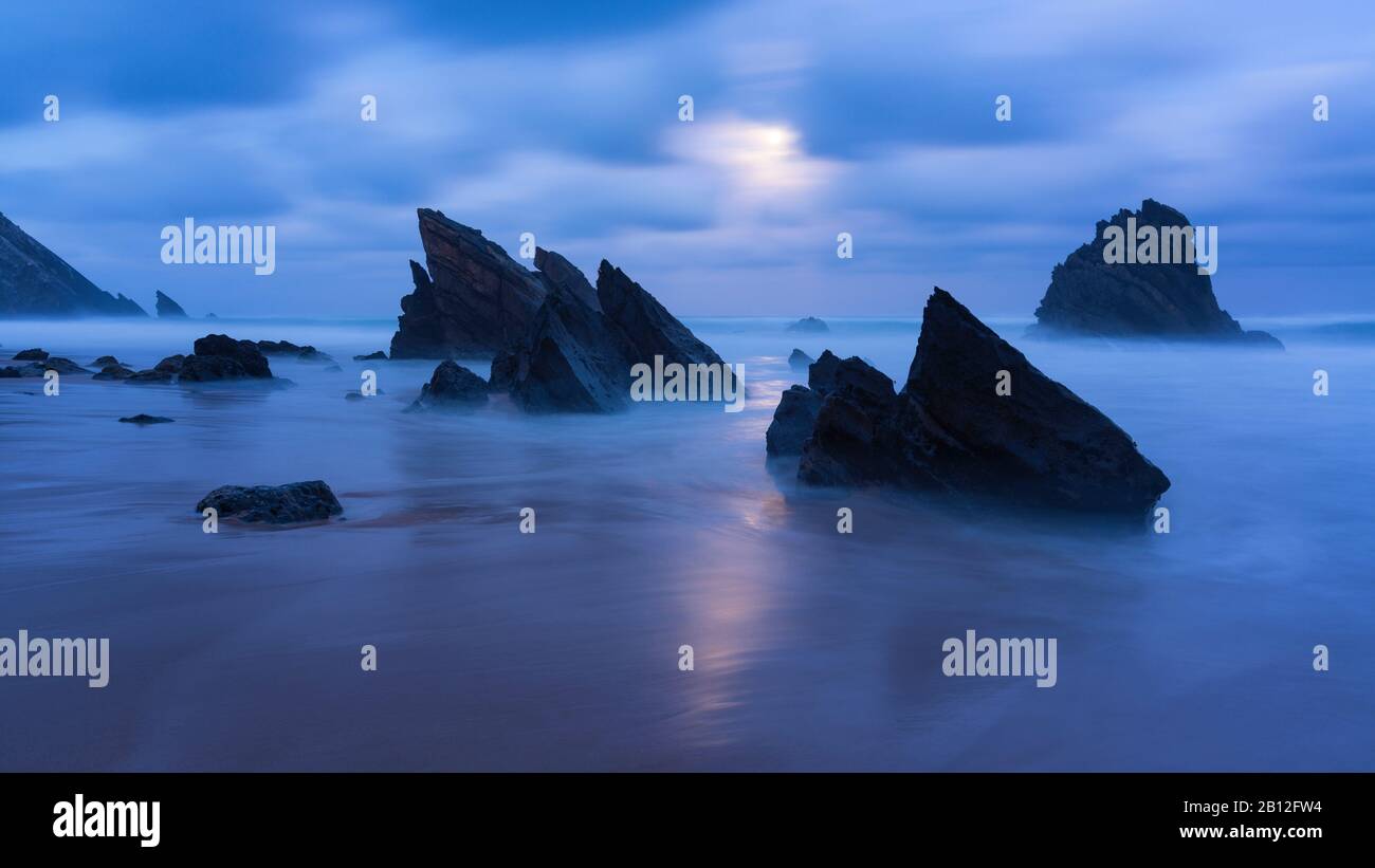 Clair de lune sur une plage de sable avec des formations rocheuses, Praia da Adraga, Sintra, Portugal Banque D'Images