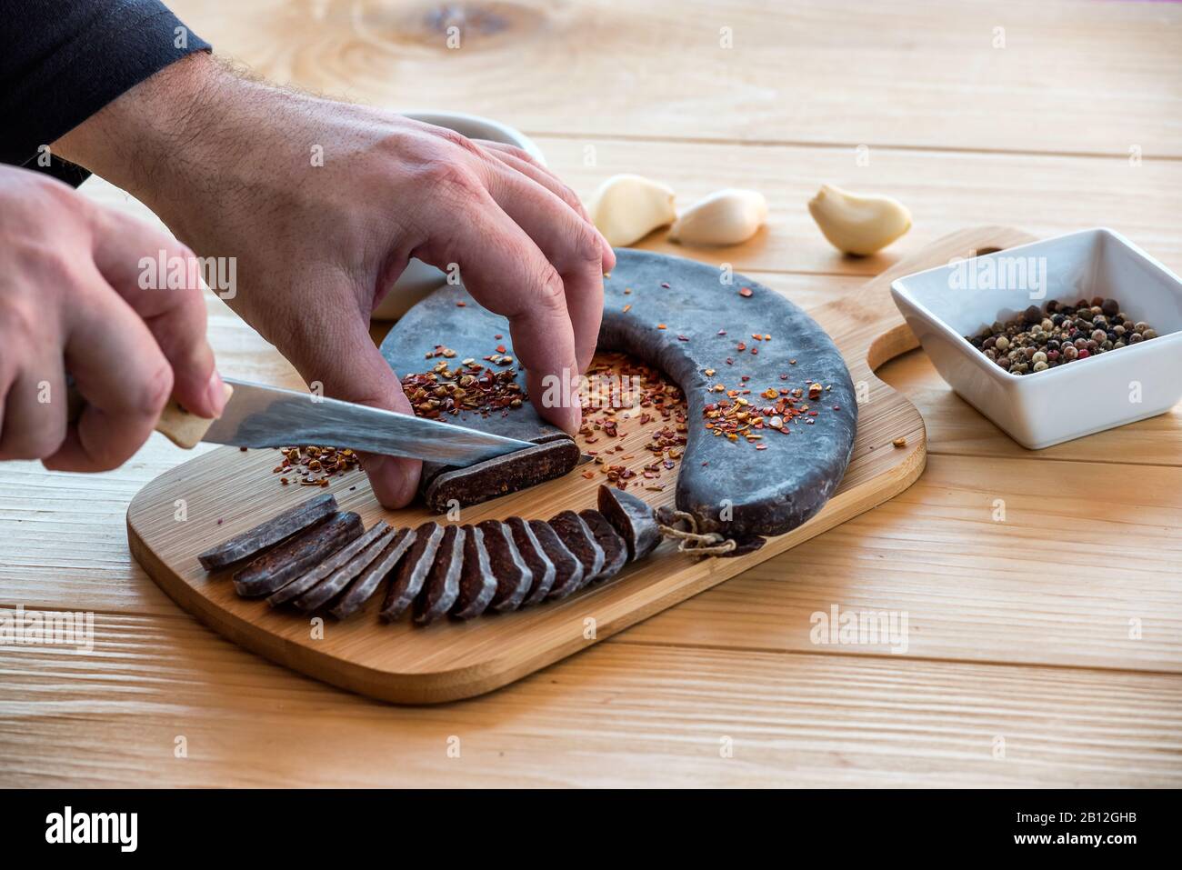 Les Mains de l'homme coupent Des Tranches de saucisse spéciale en fer à cheval Pirot - Peglana Pirotska kobasica, faite de viande de veau, de mouton et de chèvre Banque D'Images