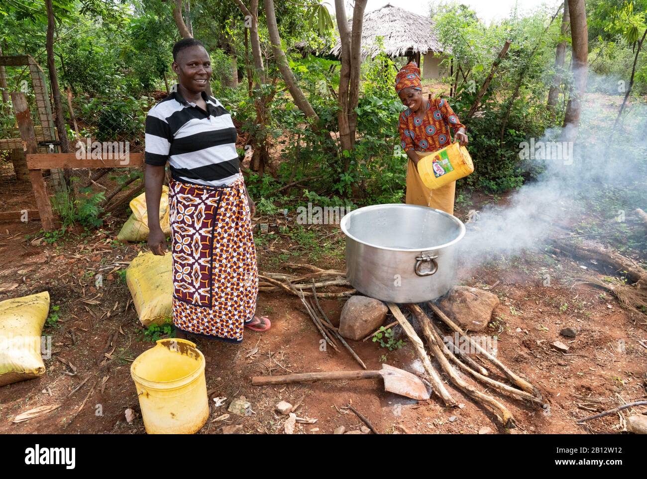 Dîner femmes préparant le déjeuner dans une énorme pot en aluminium sur un feu ouvert pour les enfants dans une école primaire kenyane à Sagalla près De Voi Sud Kenya Banque D'Images