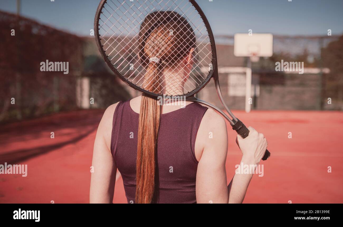 Belle et mince fille avec un raquette joue au tennis, fille se tient avec son dos à la visionneuse Banque D'Images