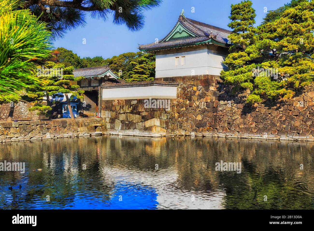 Des tours historiques blanches sur des murs en pierre autour du palais impérial dans la ville de Tokyo, entourées d'une foule d'eau par une journée ensoleillée. Banque D'Images