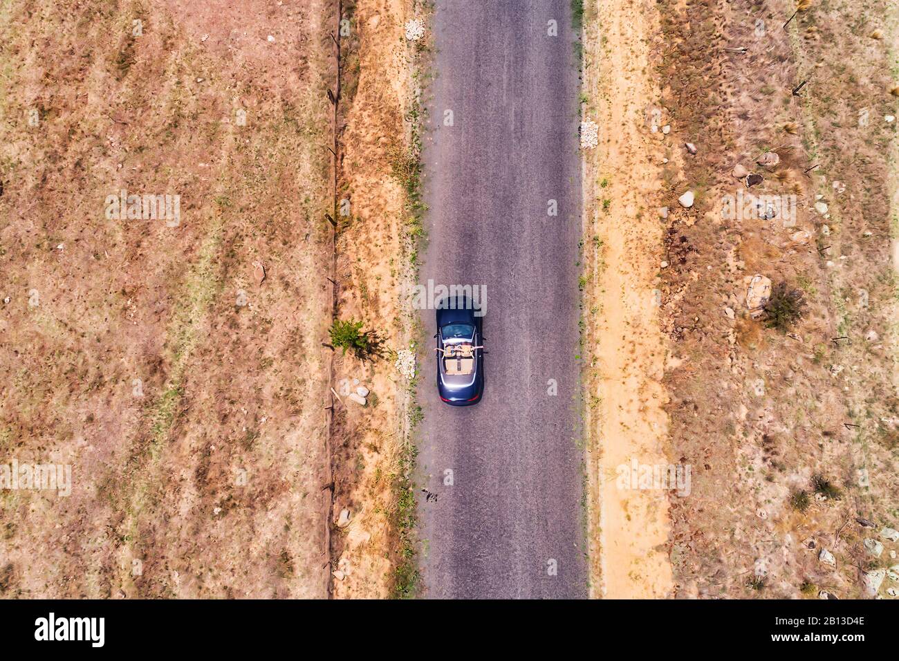 Fermes agricoles rurales éloignées le long de la route à une voie dans les montagnes Bleues australiennes avec voiture cabriolet de voyageurs conduisant des gens de vacances heureux. Banque D'Images