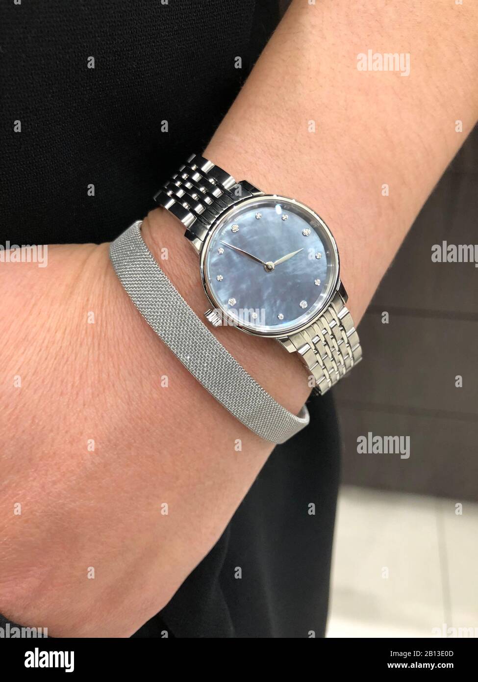 Montre en métal argenté avec un visage bleu de perle et des diamants et bracelet sur le poignet de la dame Banque D'Images