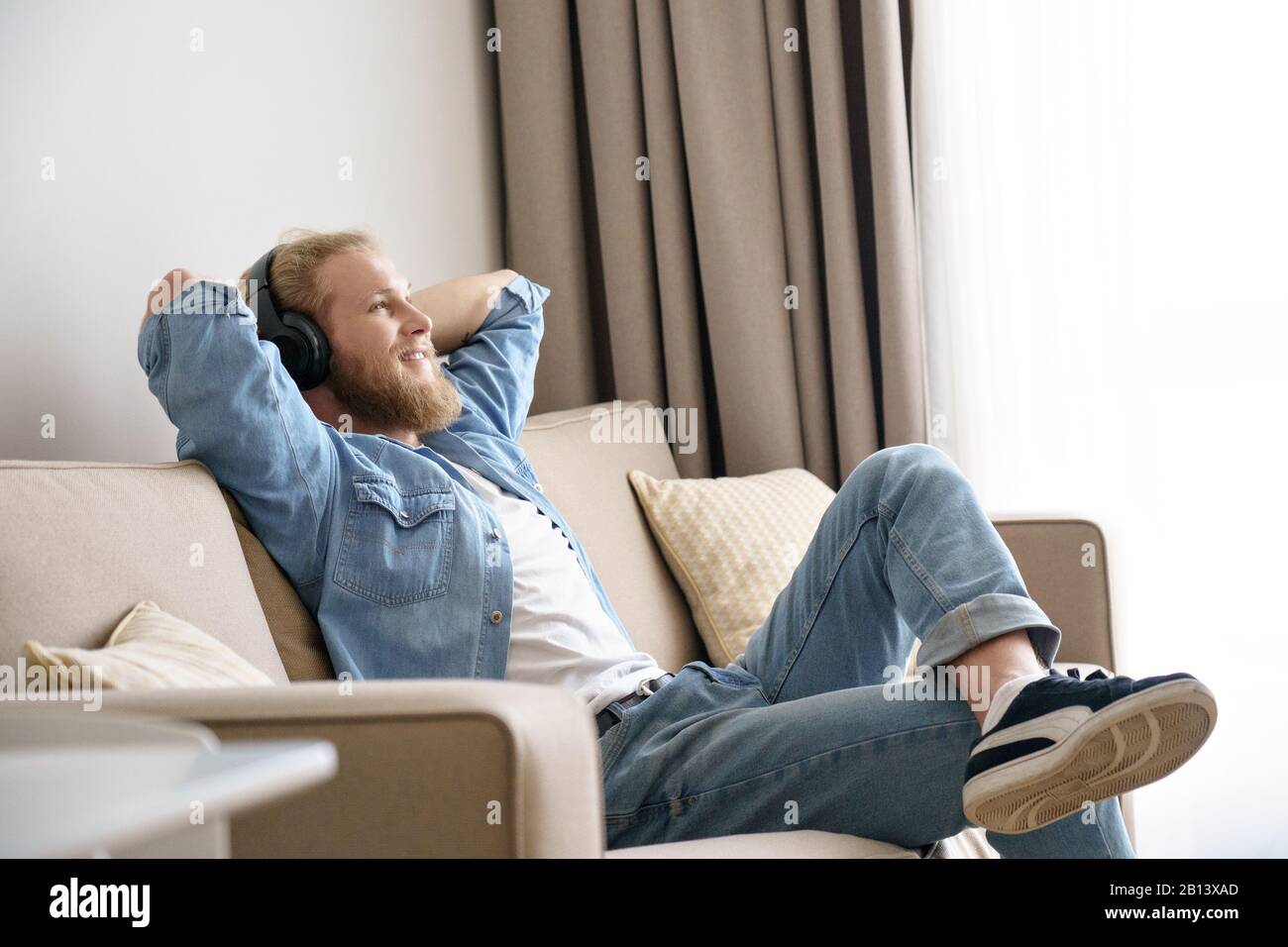 Un salon pour jeunes hommes décontracté sur un canapé porte un casque à  écouter de la musique Photo Stock - Alamy