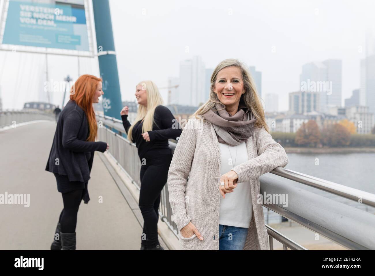 Une femme d'âge moyen est debout avec deux jeunes femmes sur un pont Banque D'Images