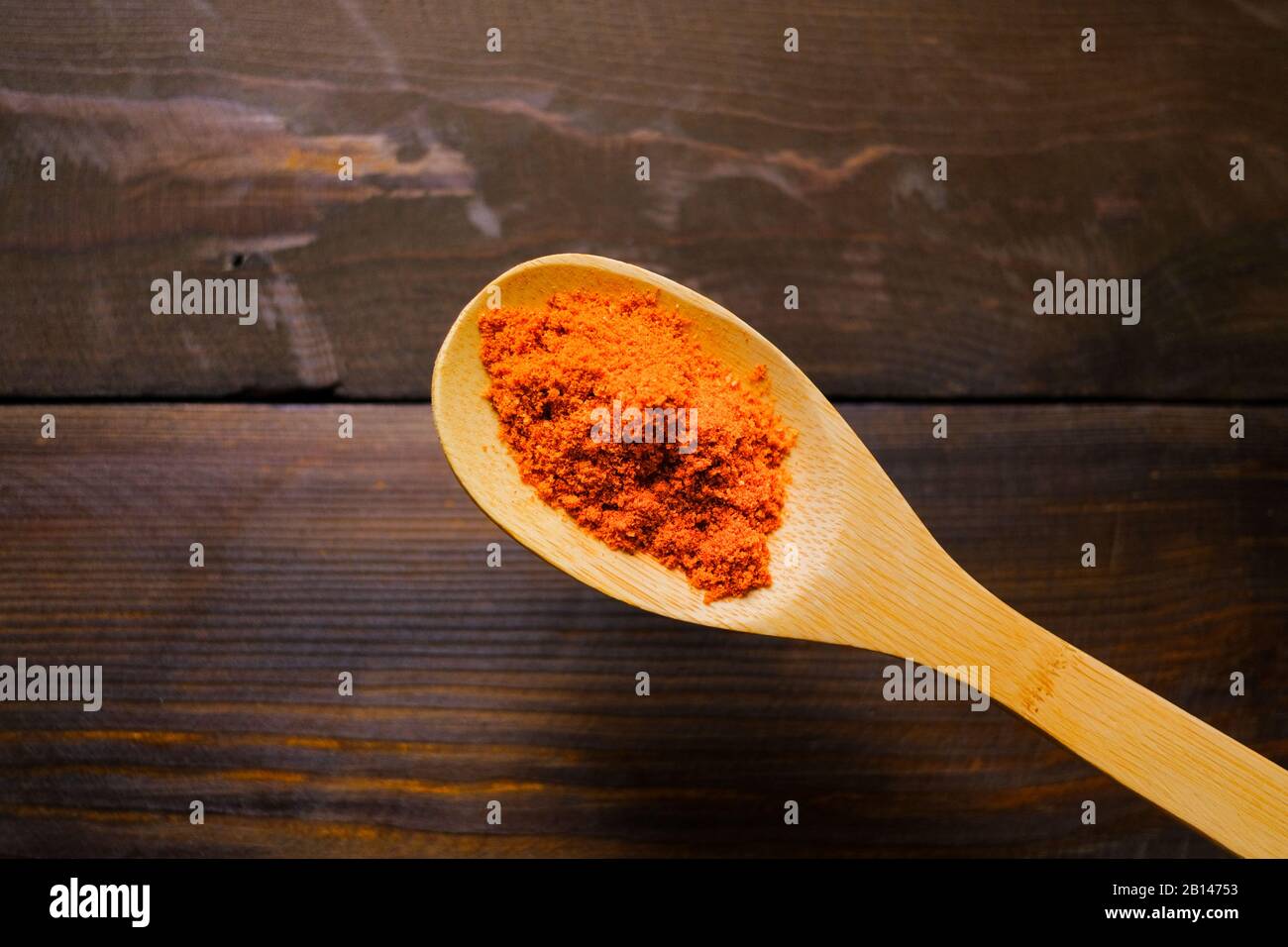 Épices orange vif sur une cuillère en bois. Banque D'Images