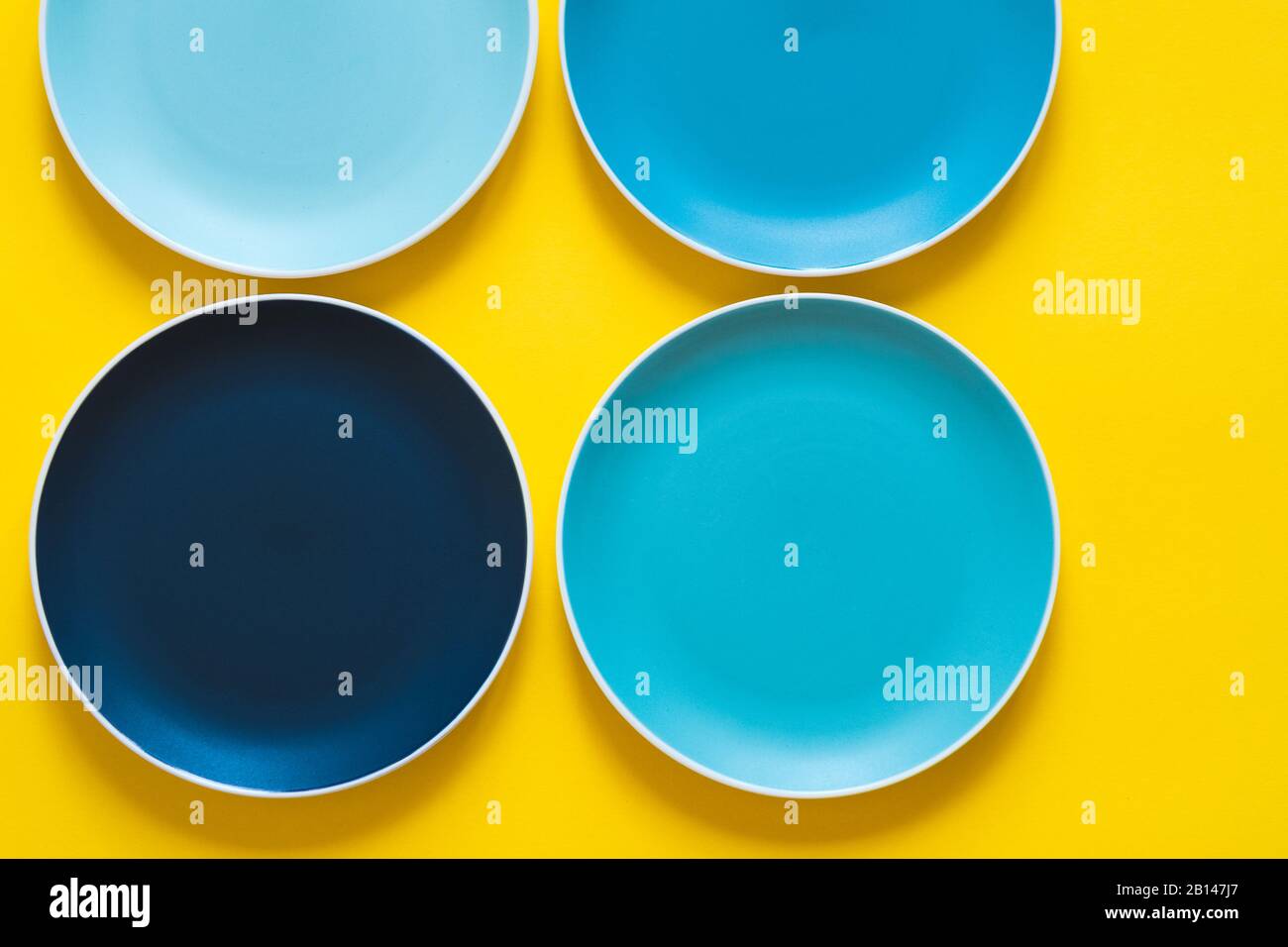 Plaques en céramique bleu pastel colorées isolées sur fond jaune. Banque D'Images