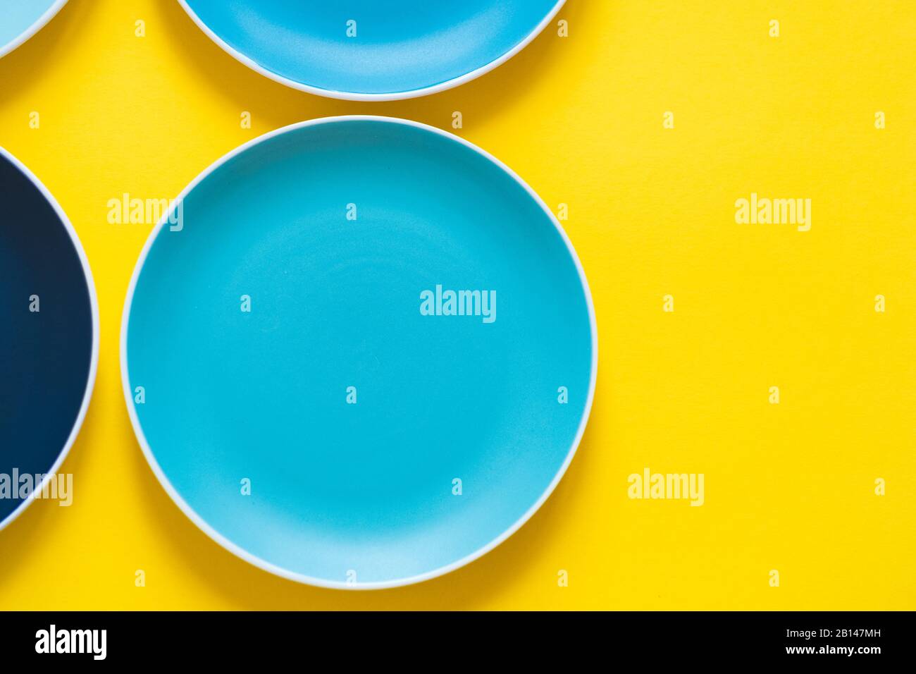 Plaques en céramique bleu pastel colorées isolées sur fond jaune. Banque D'Images