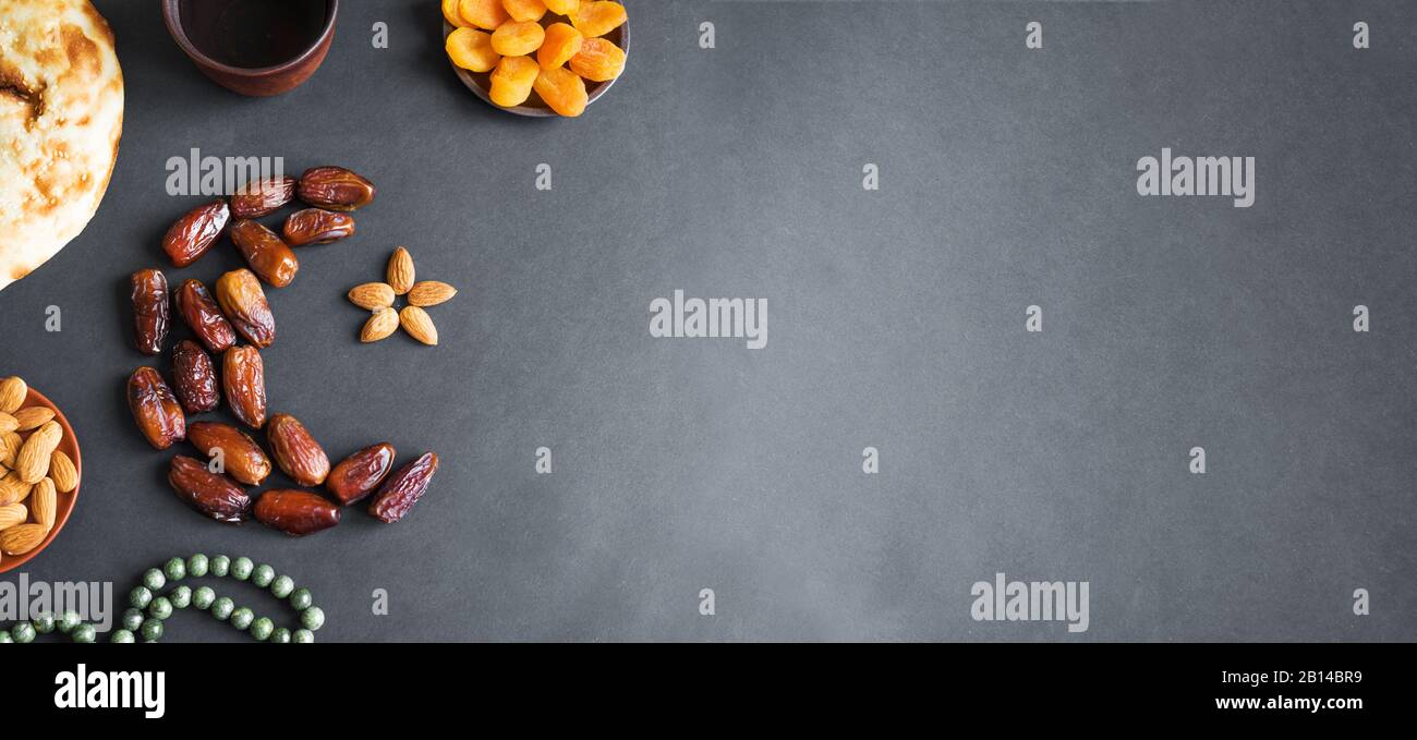 Ramadan Kareem musulman avec dates fruits disposés en forme de croissant de lune, eau et pain sur fond noir, bannière, espace de copie. Ftar fête conce Banque D'Images
