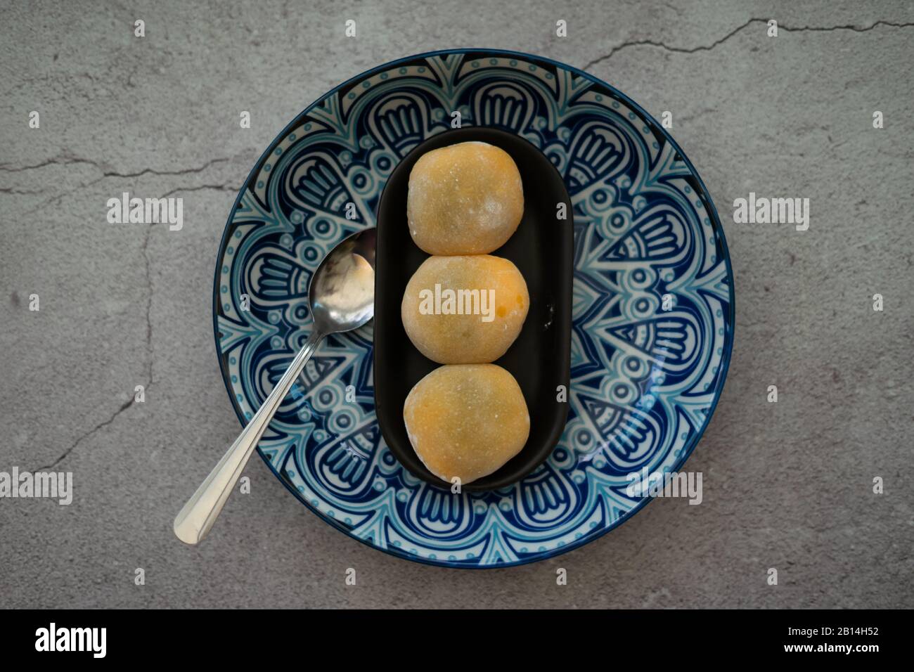 Mochi japonais de couleur jaune dans la pâte de riz et sur un fond de plaque bleu motif. Dessert japonais traditionnel. Banque D'Images