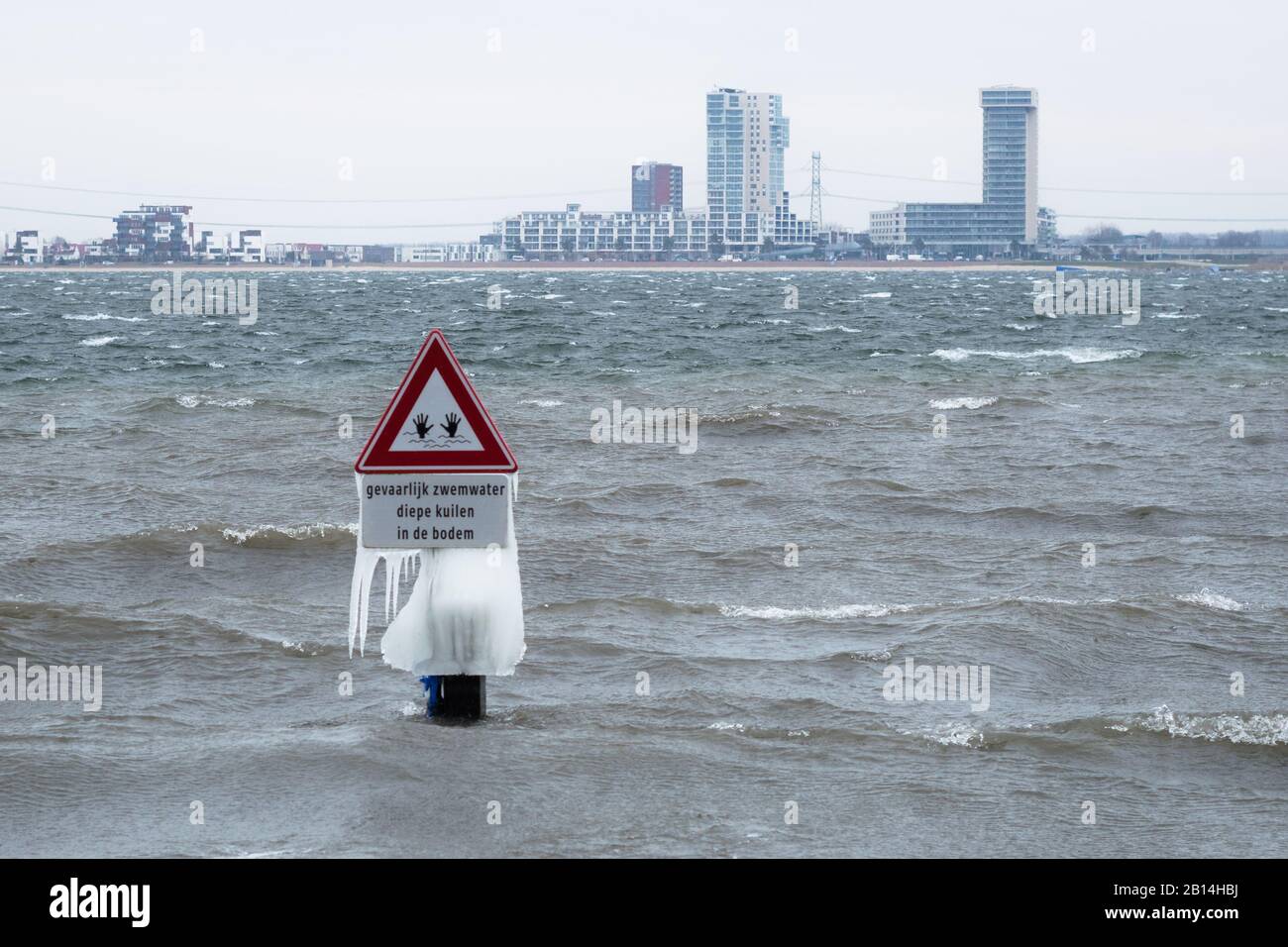 Icicles sur un panneau d'avertissement dans un lac pendant un sort très froid en fin d'hiver. Le texte néerlandais signifie « l'eau de baignade, les fosses profondes au fond ». Banque D'Images